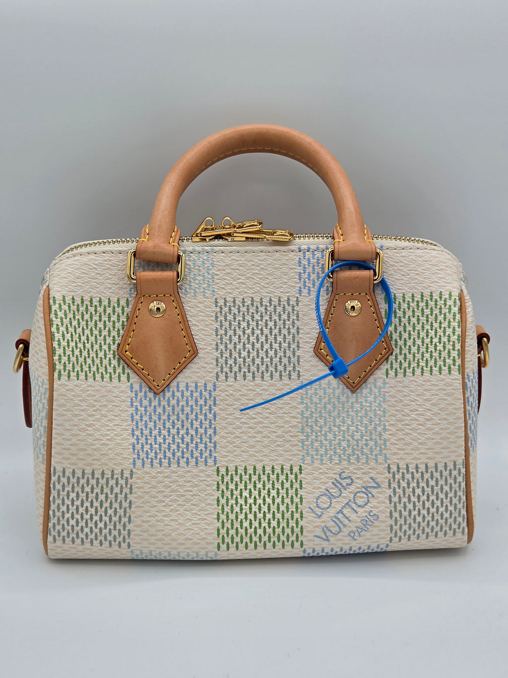 Patterned handbag with brown handle and trim on a gray background