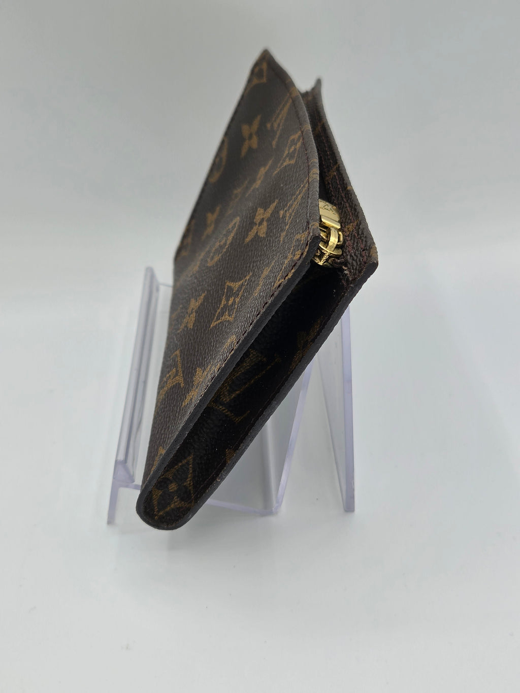 Louis Vuitton wallet on a clear stand against a white background