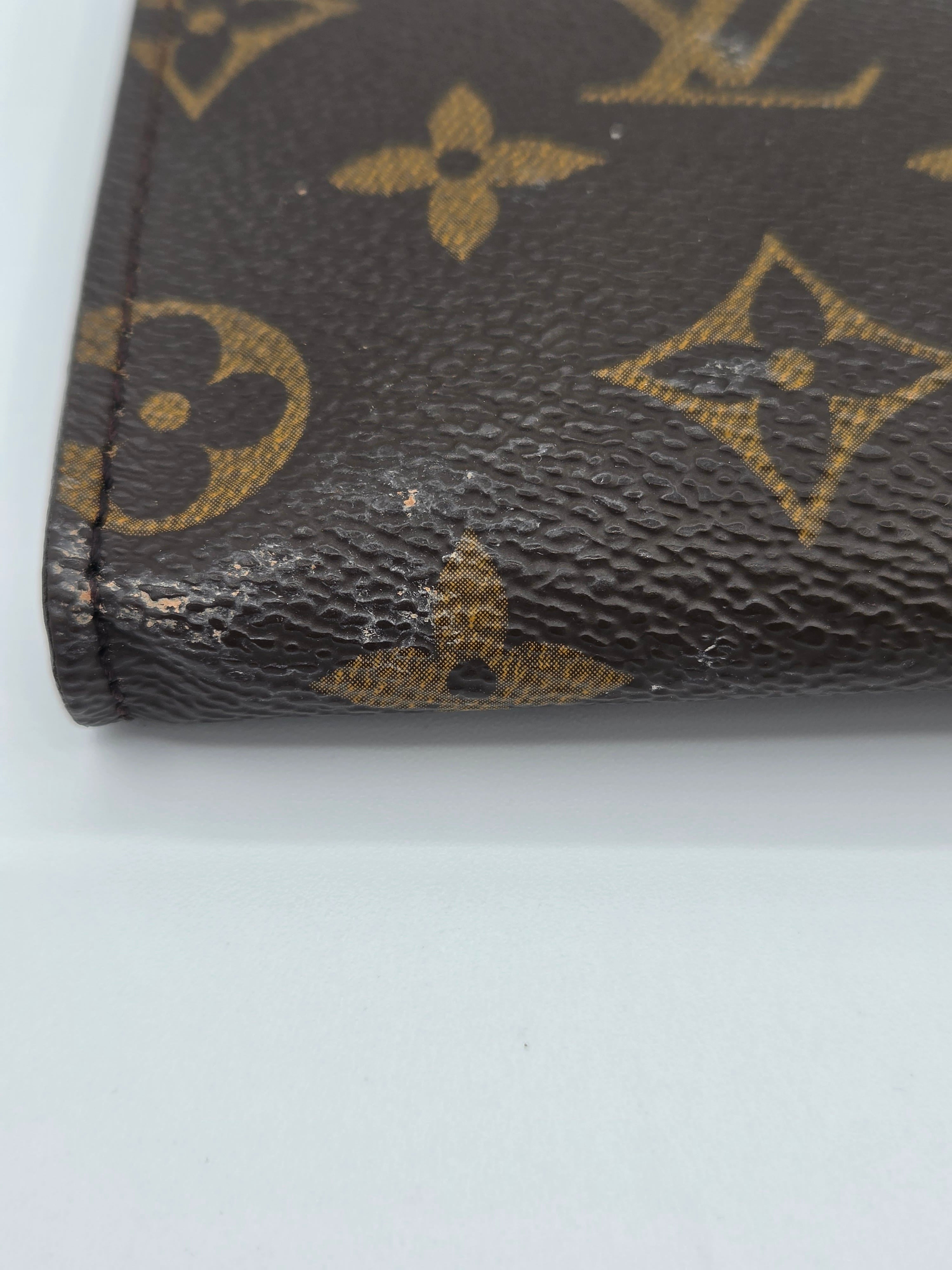 Close-up of a Louis Vuitton wallet corner with visible wear on a white background