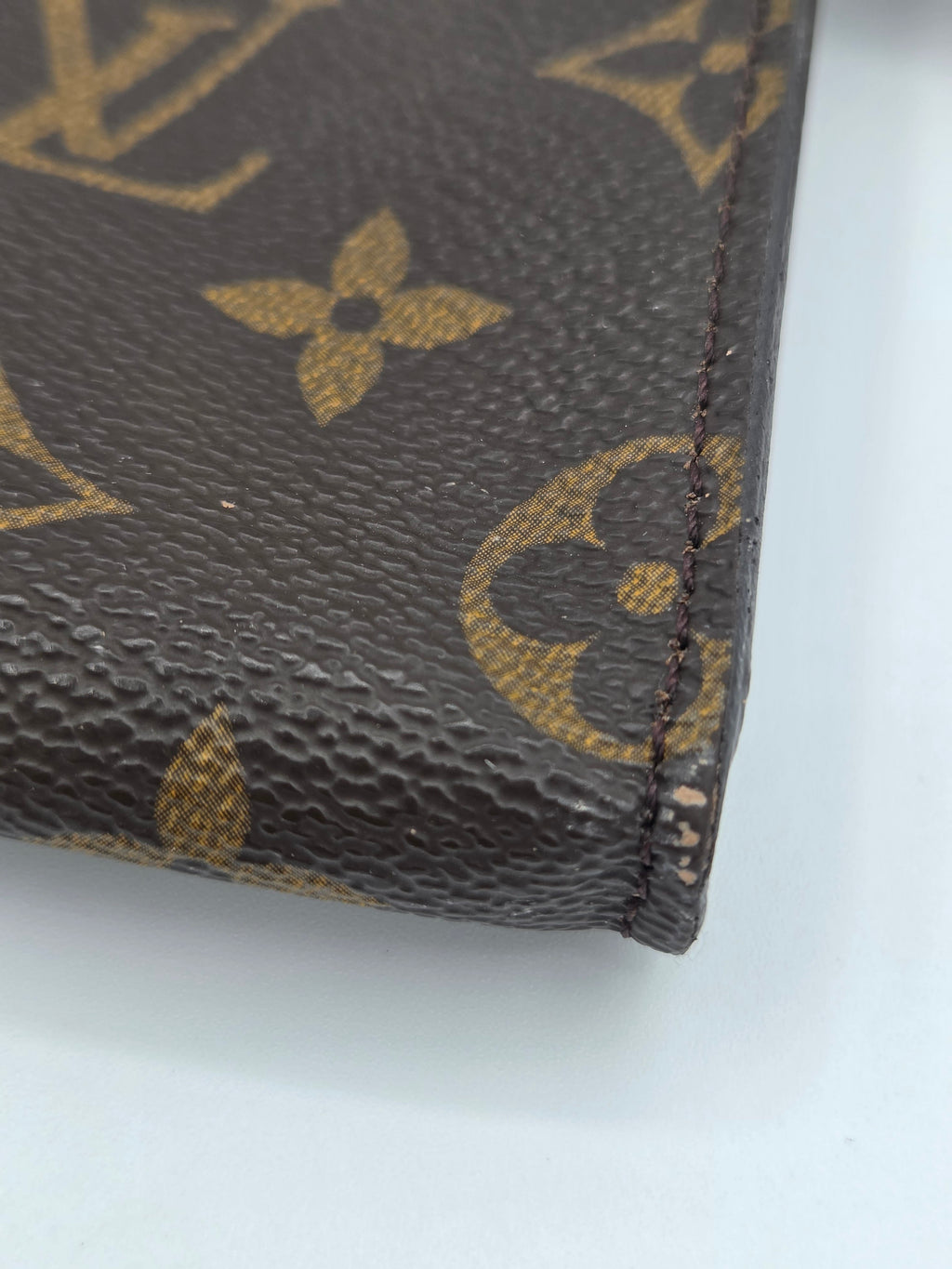 Close-up of a Louis Vuitton wallet with monogram pattern on a white background