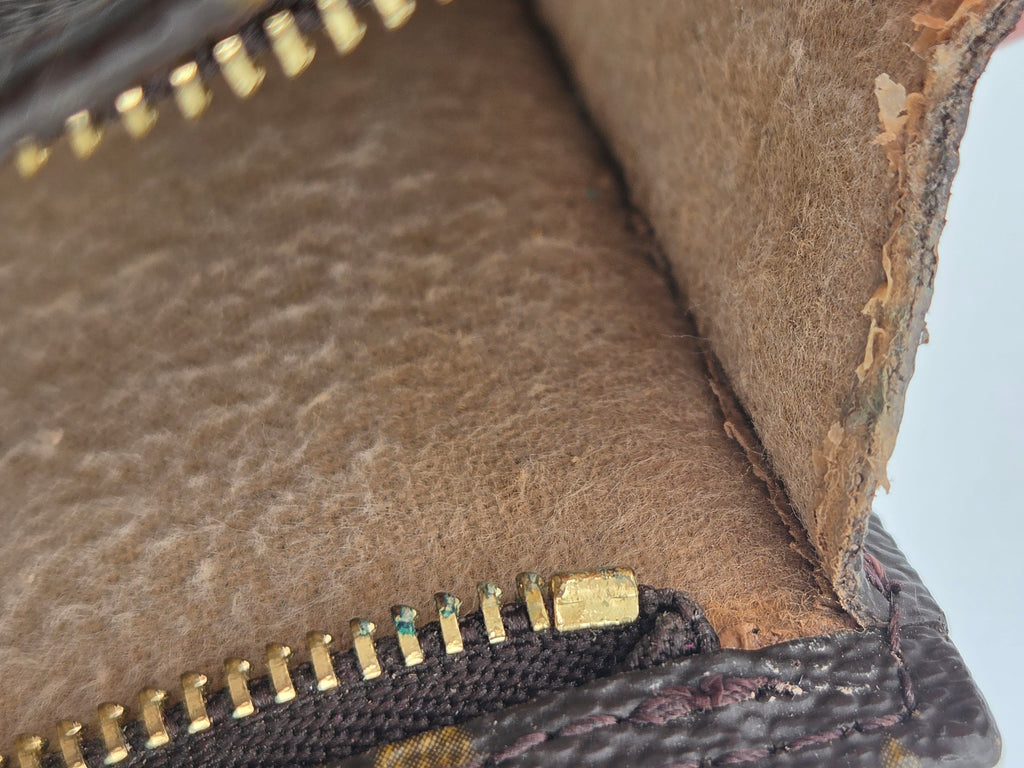 Close-up of a leather wallet with gold zipper details on a light gray background