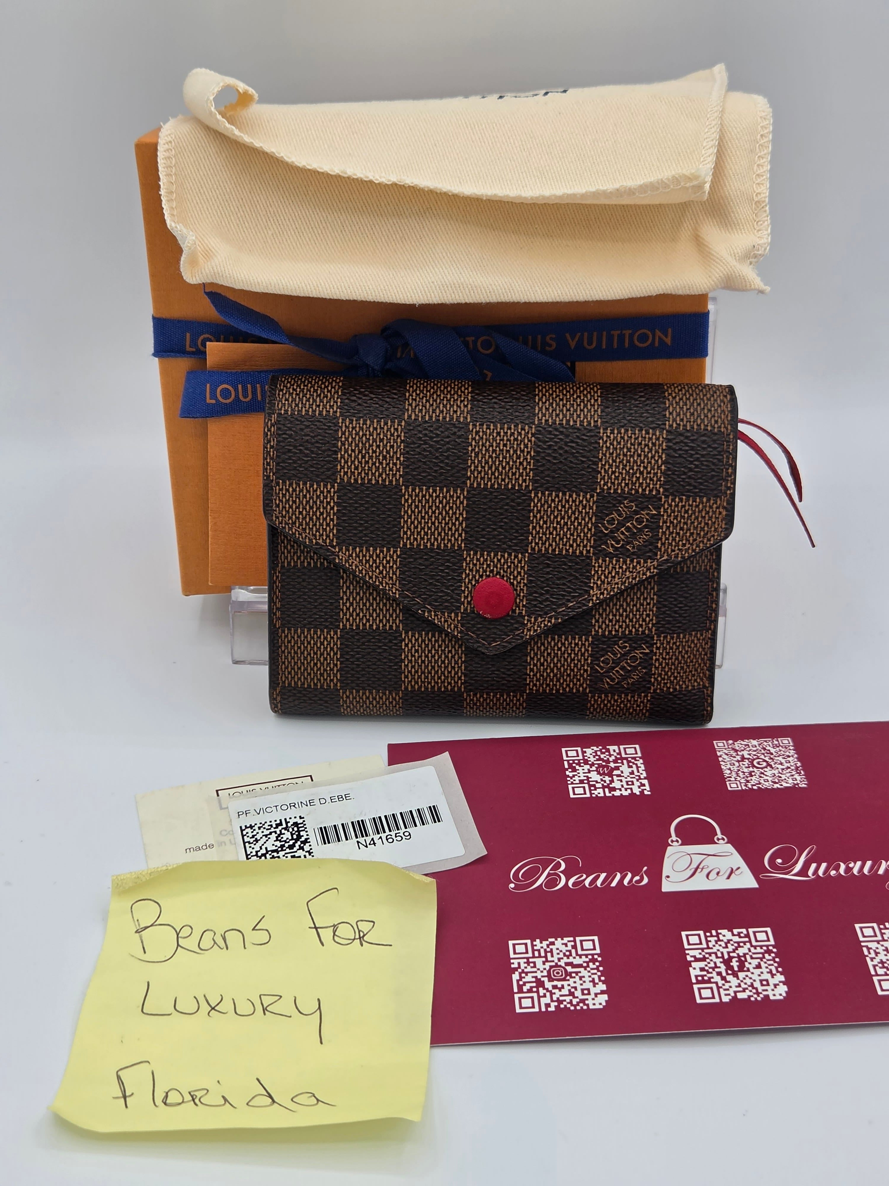 Designer wallet with checkered pattern, branded box, and tags on a white background
