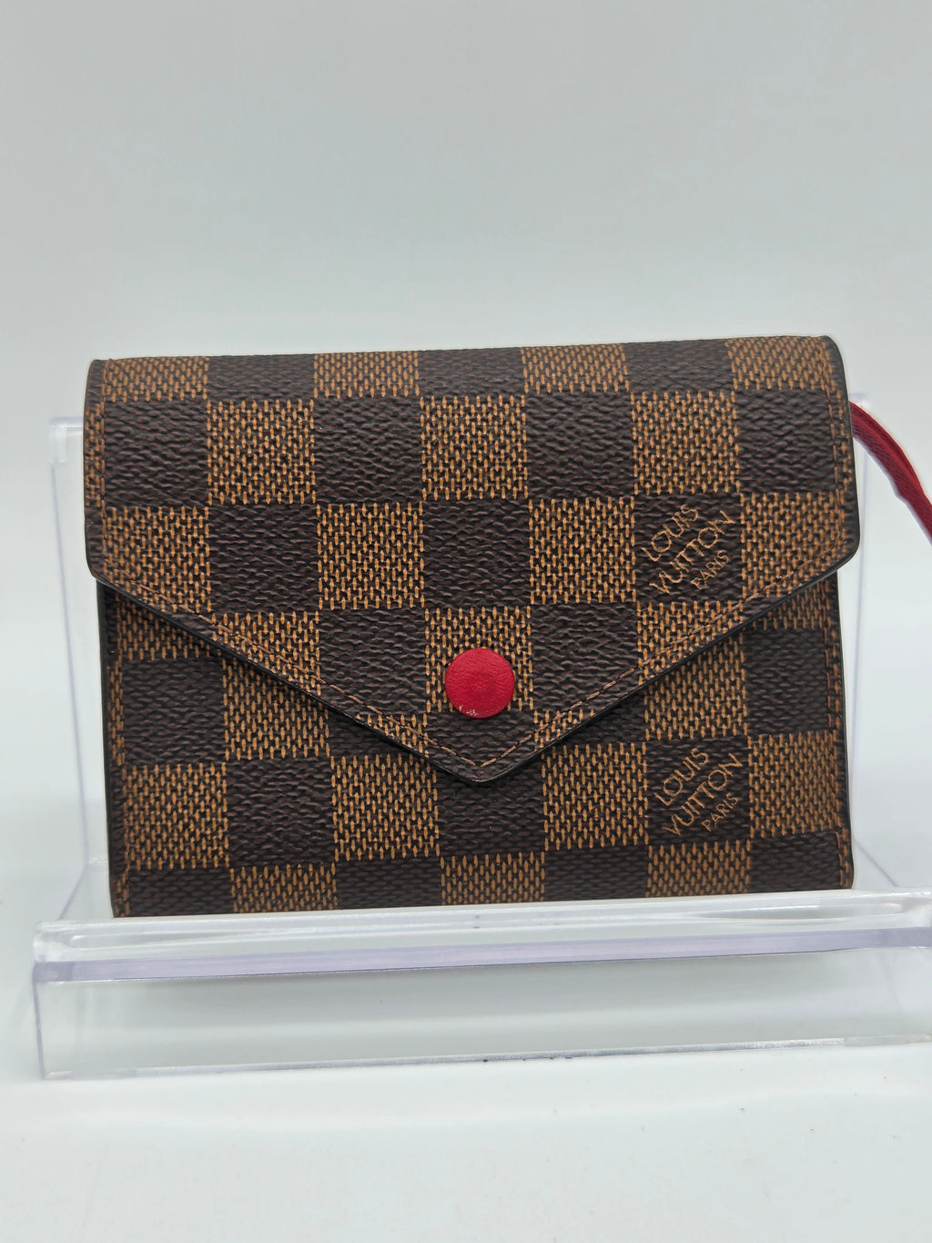Designer wallet with checkered pattern and red button on a white background