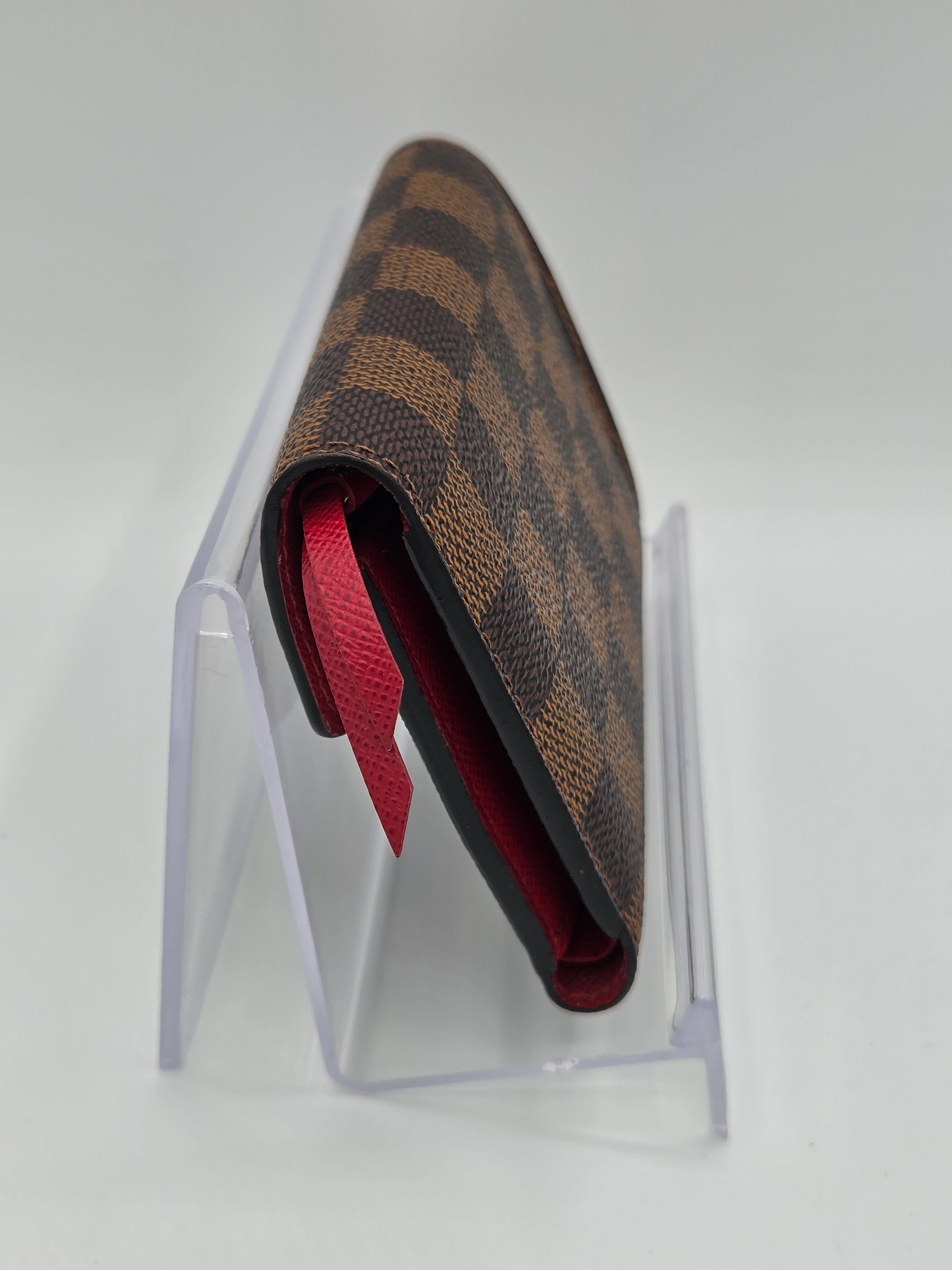 Designer wallet with red interior on a clear stand against a light gray background
