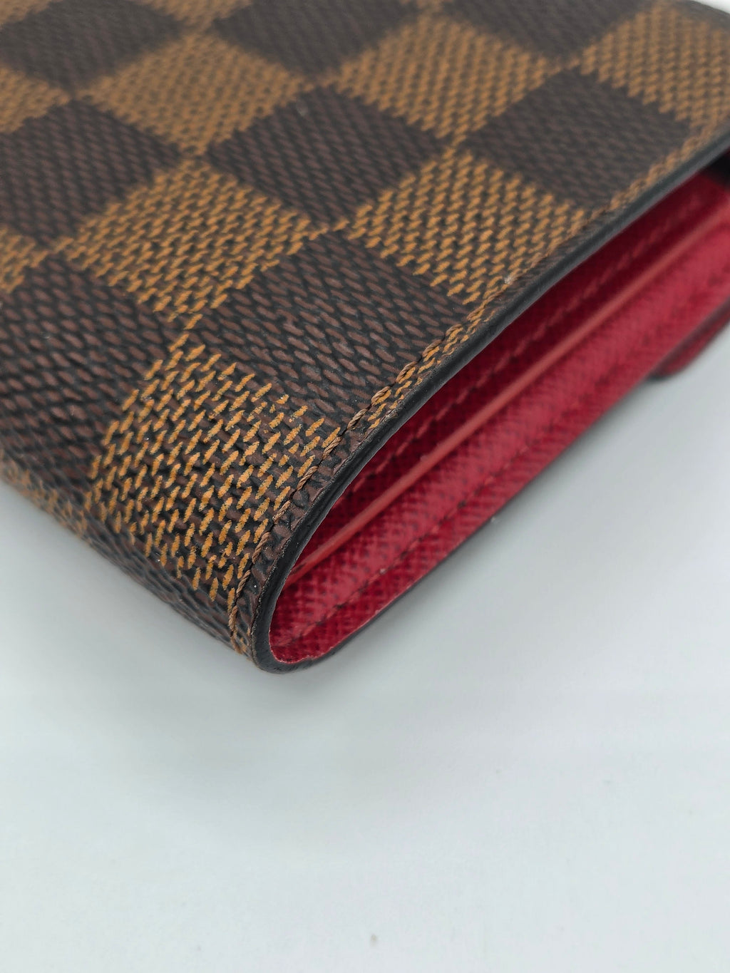Close-up of a brown checkered wallet with a red interior on a white background