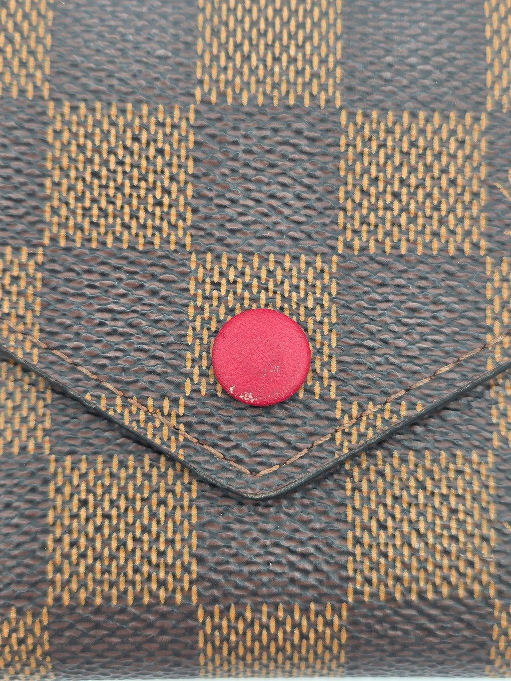 Close-up of a textured fabric with a red button and checkered pattern