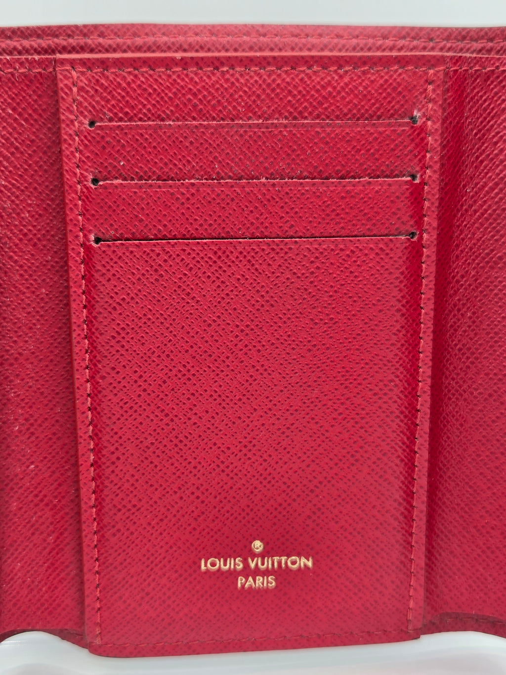 Close-up of a red Louis Vuitton wallet with visible branding.