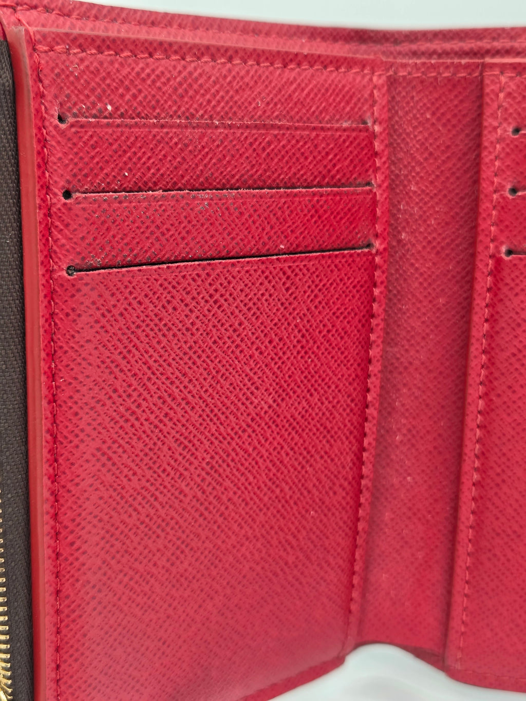 Close-up of a red wallet with visible stitching on a white background
