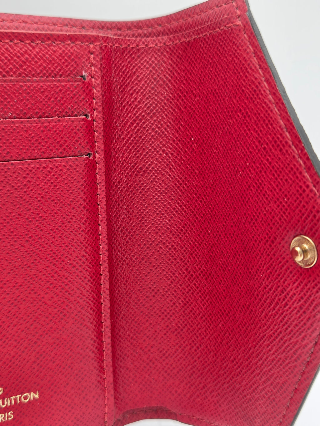 Close-up of a red wallet with a gold buckle on a white background