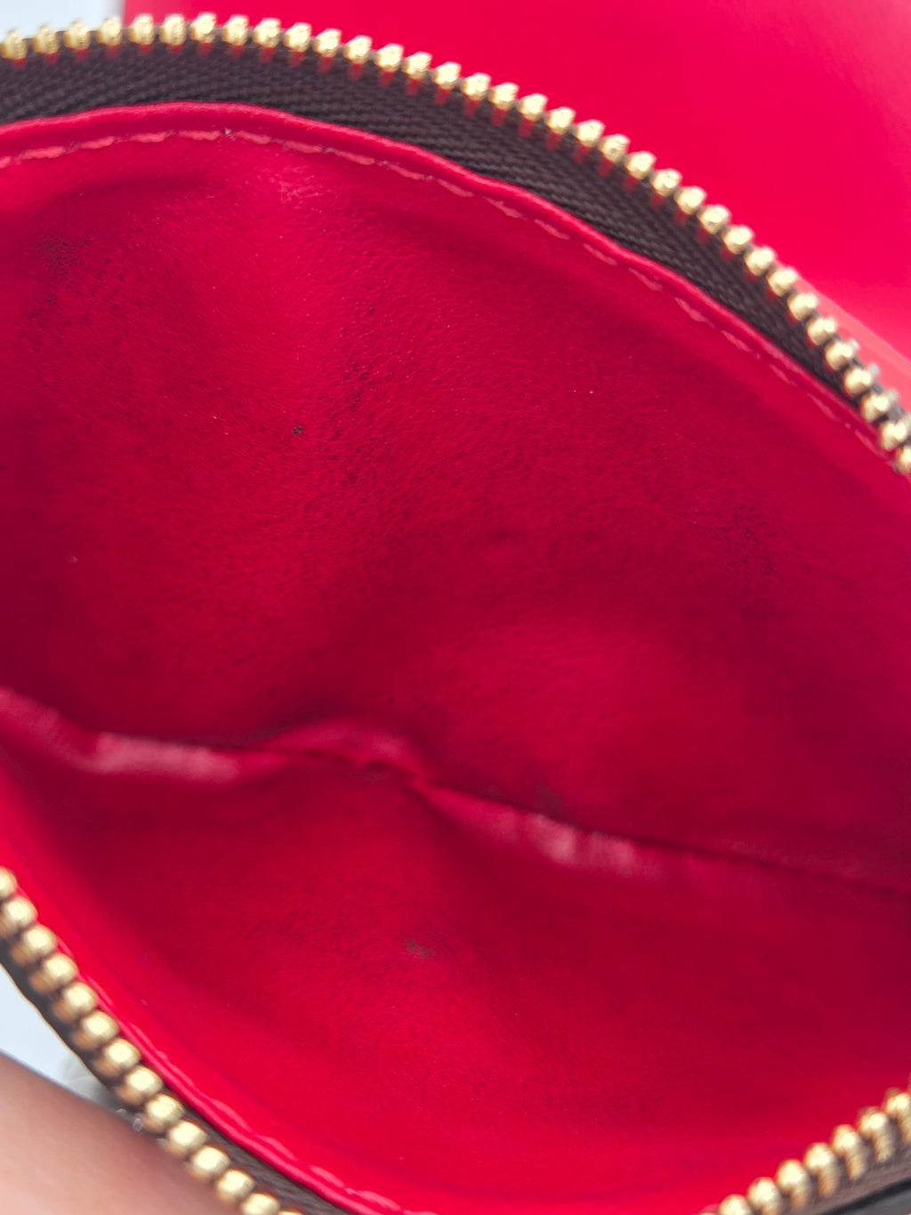 Close-up of a red leather handbag with gold zipper