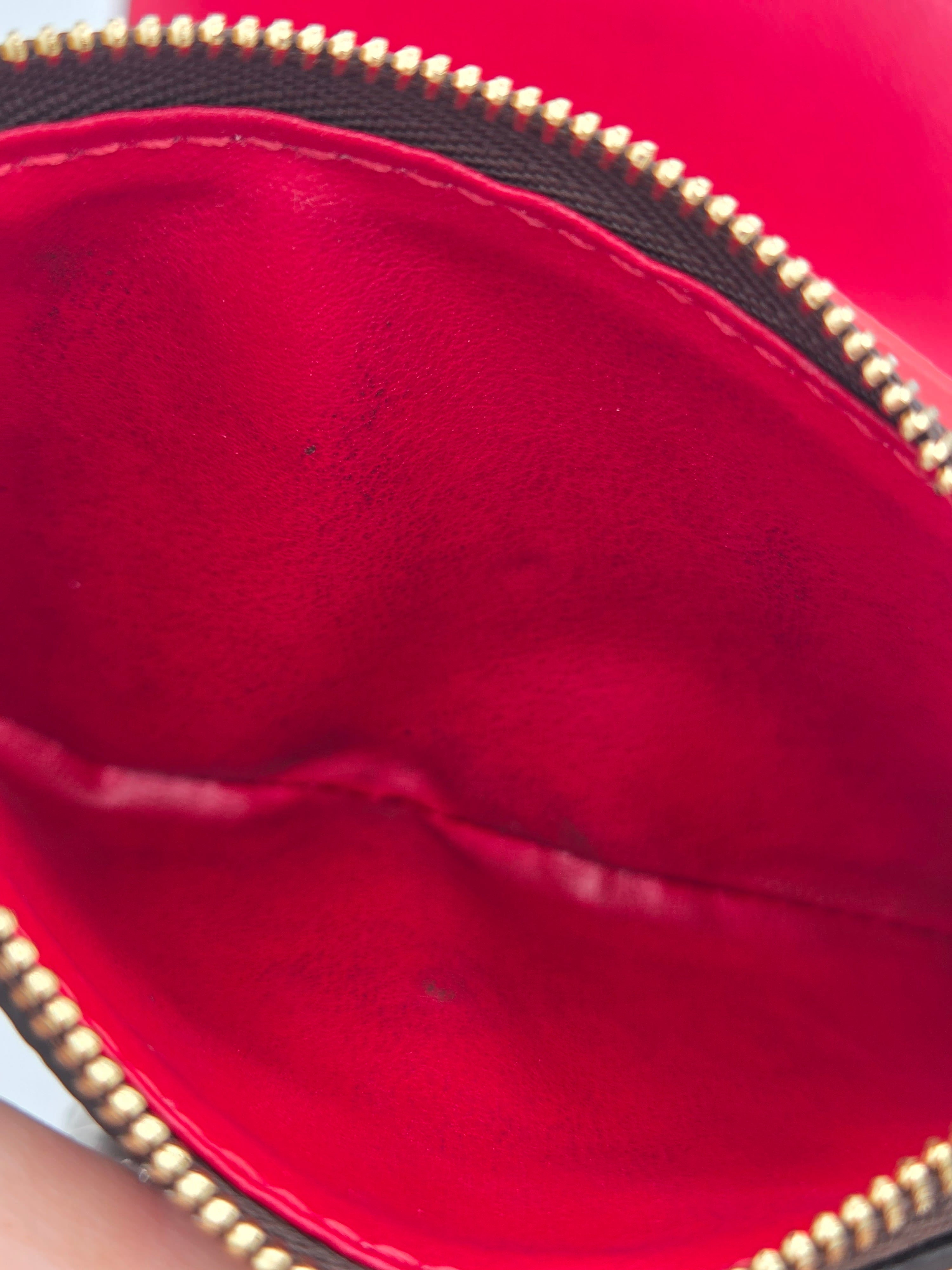 Close-up of a red leather handbag with gold zipper