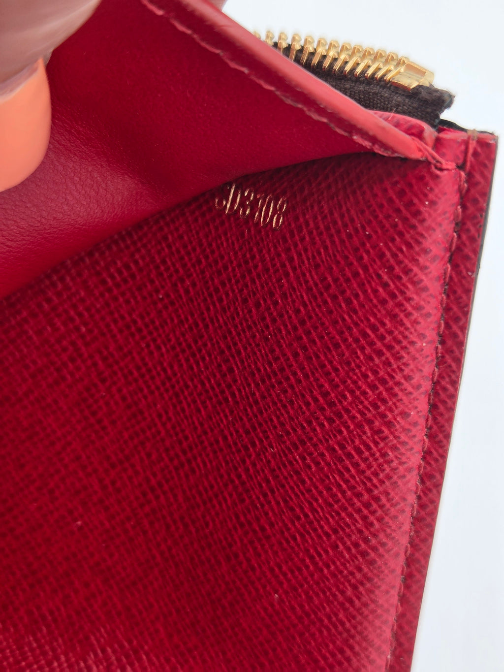Close-up of a red textured wallet with a gold zipper.