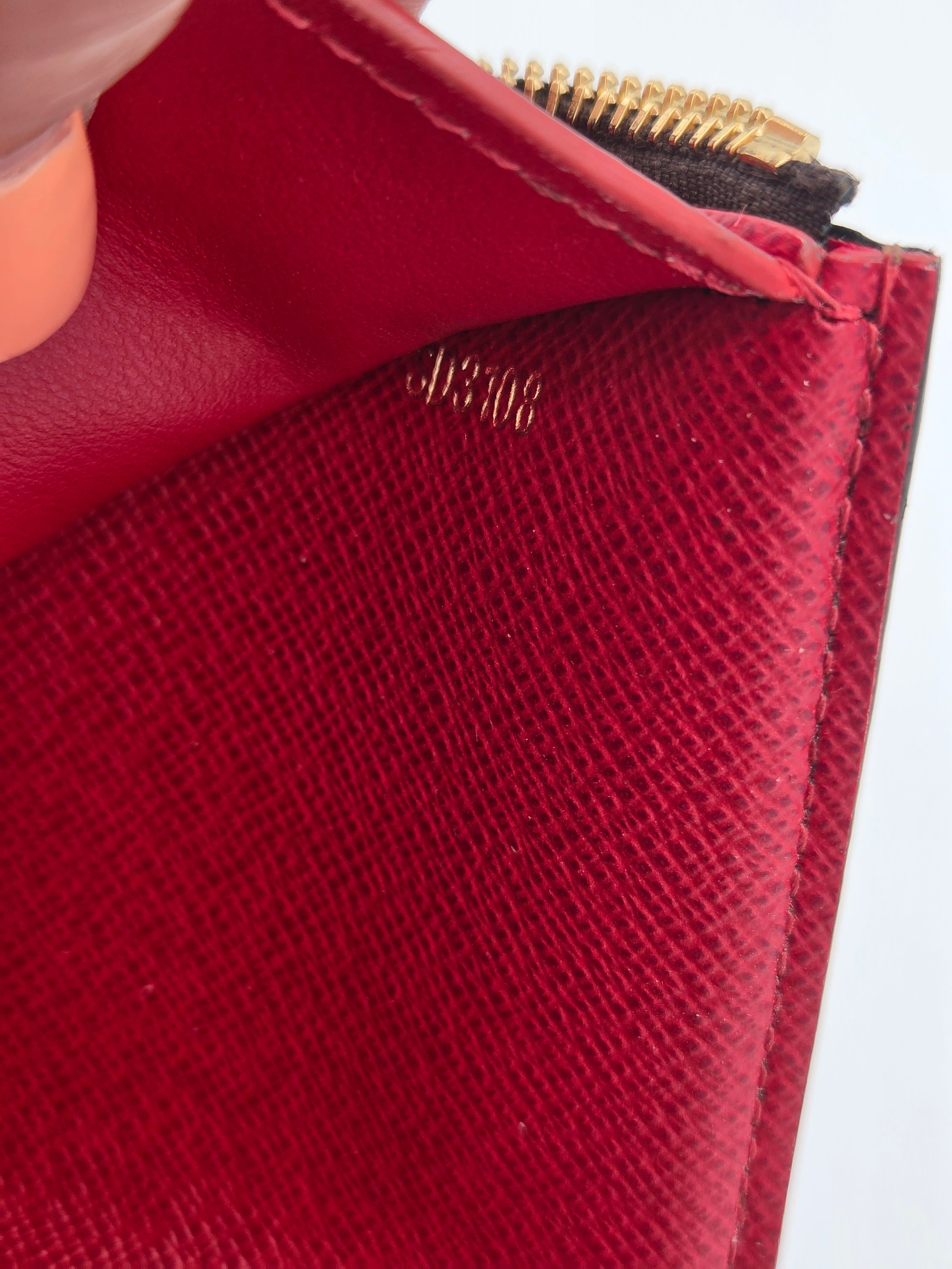 Close-up of a red textured wallet with a gold zipper.