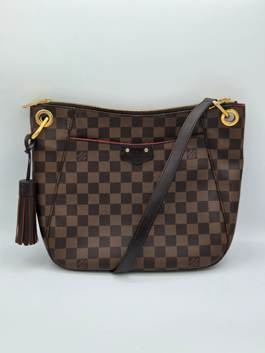 Brown checkered handbag with gold zippers on a light gray background