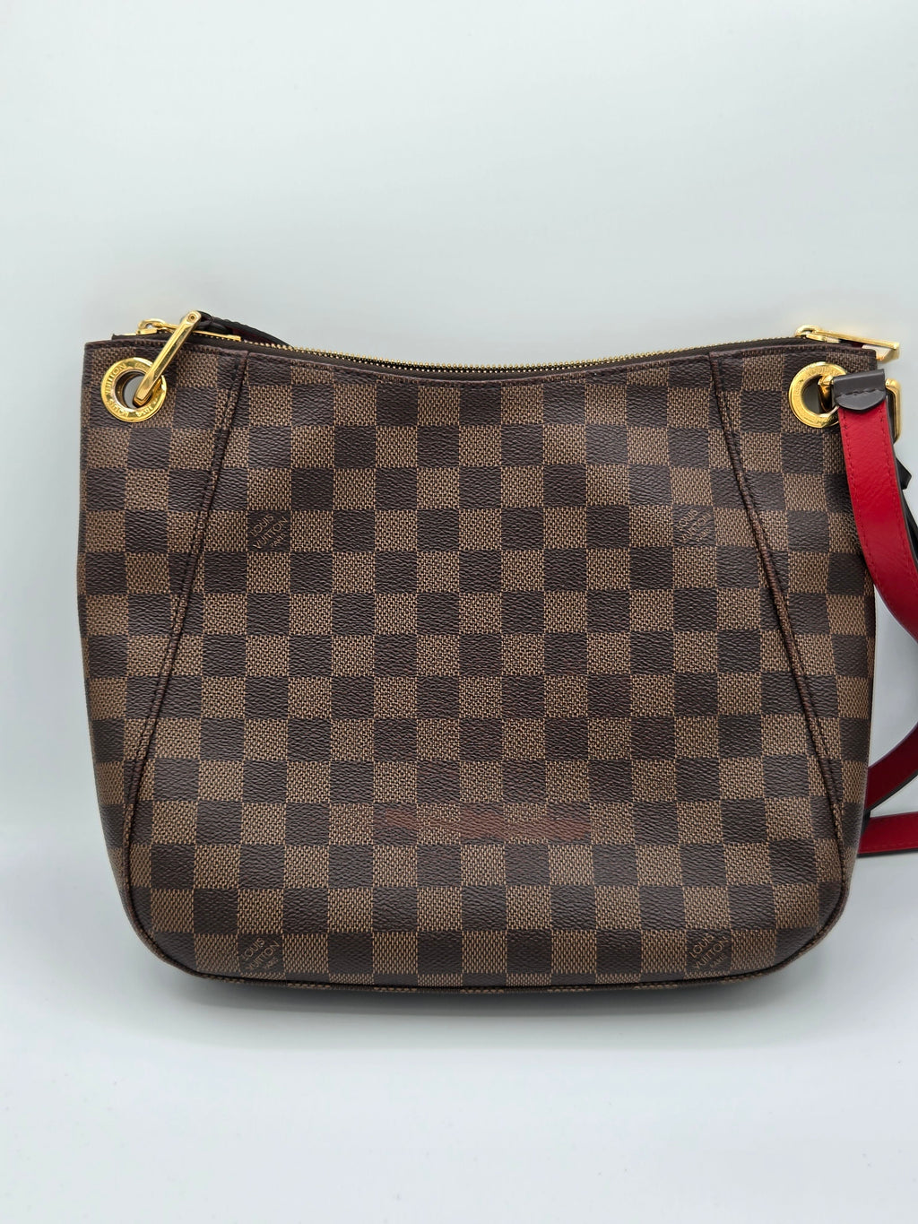 Brown checkered handbag with gold zippers on a light gray background