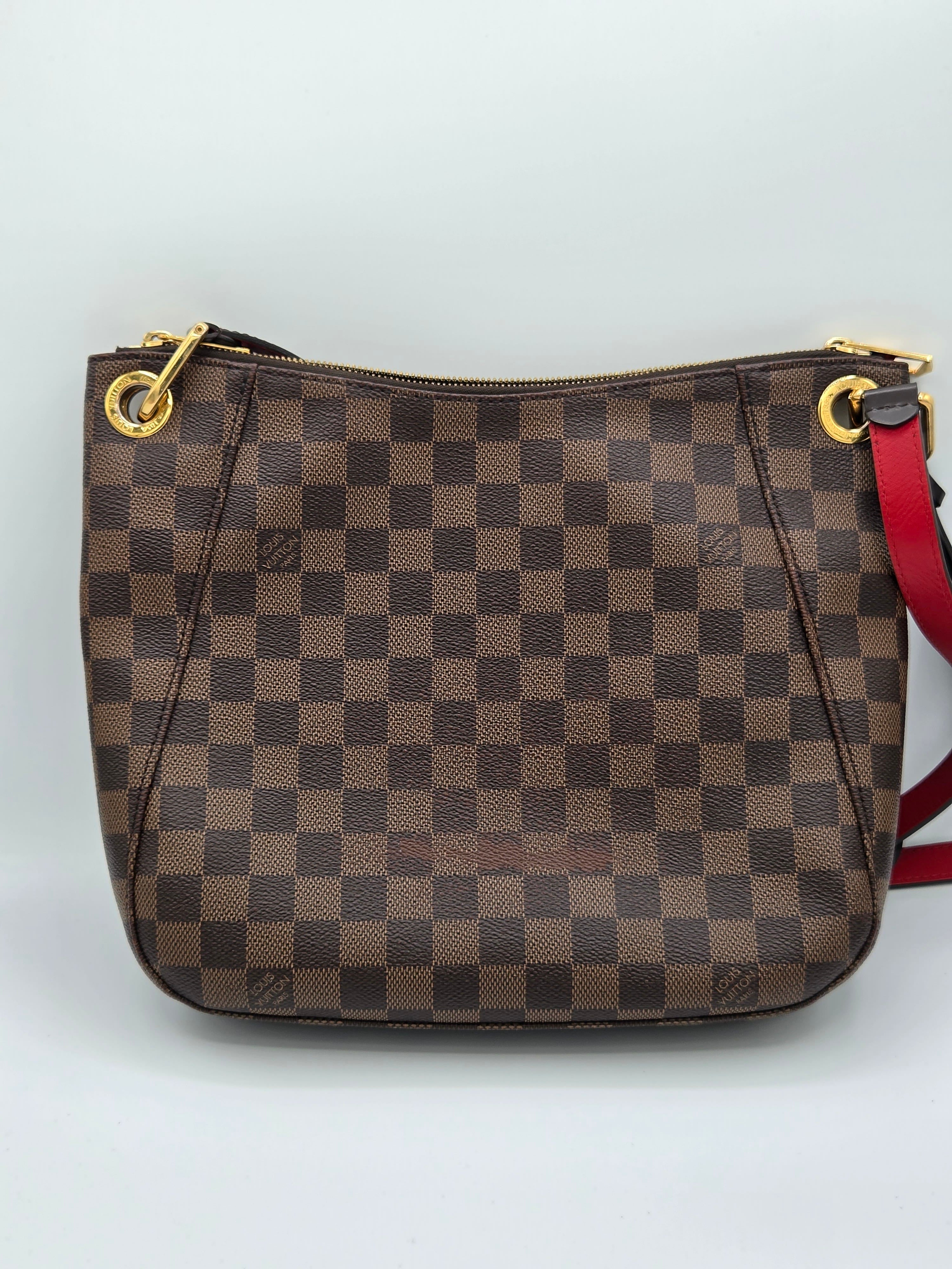 Brown checkered handbag with gold zippers on a light gray background