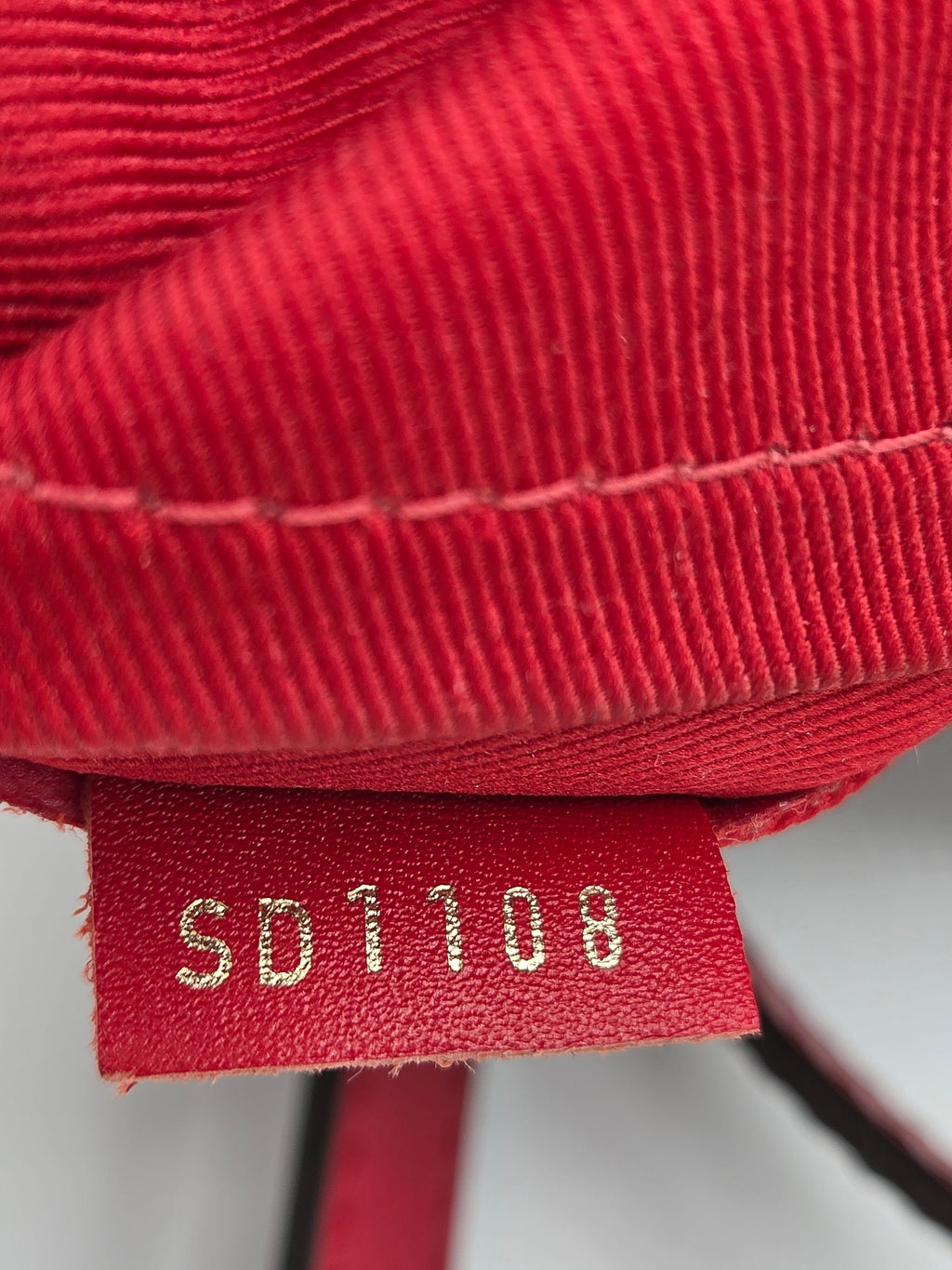 Close-up of a red textured fabric with a brand label on a white background