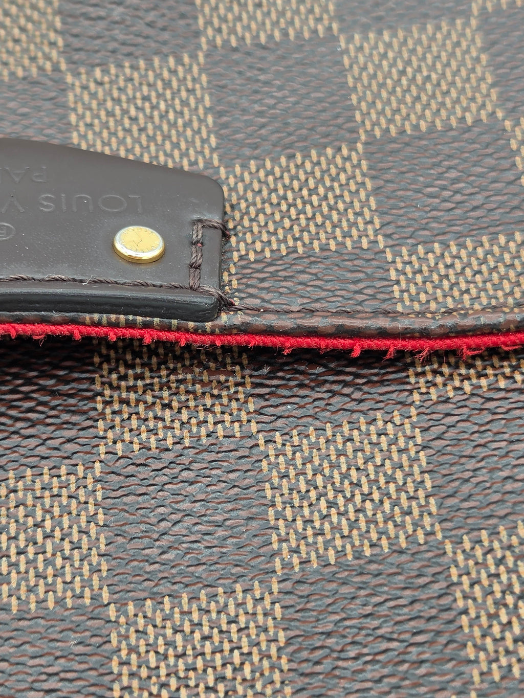 Close-up of a textured fabric surface with a brand tag and red stitching.