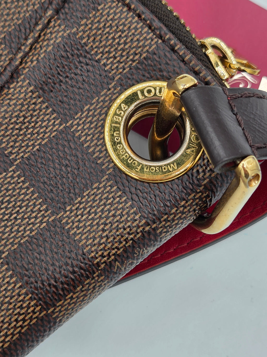 Close-up of a Louis Vuitton handbag with gold lock and checkered pattern.