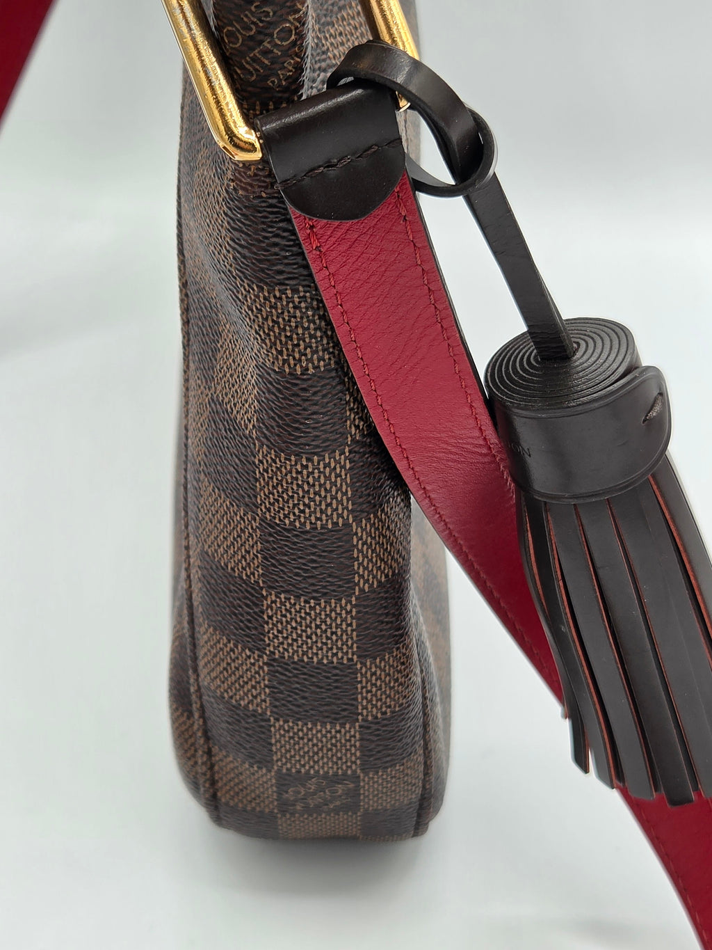 Close-up of a patterned handbag with a red strap and black tassel on a white background