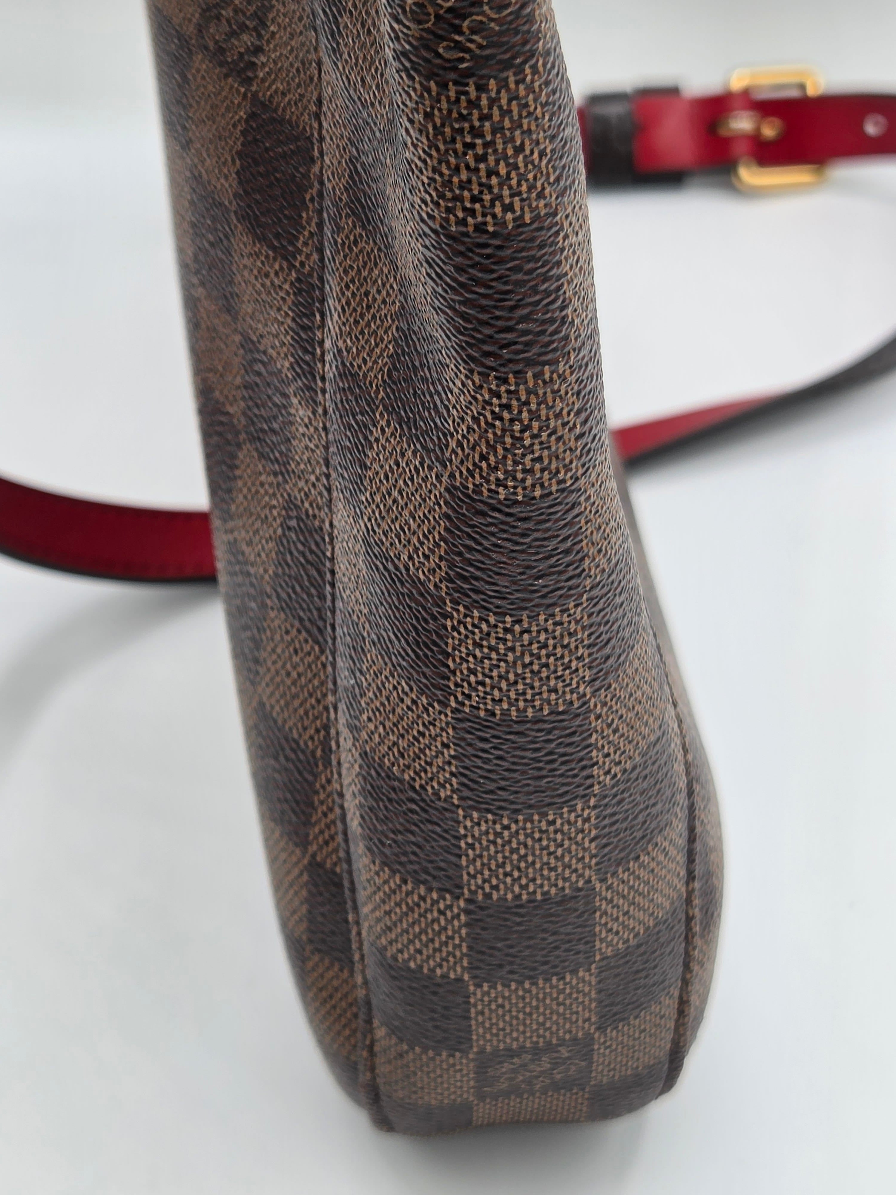 Brown checkered handbag with a red strap on a white background