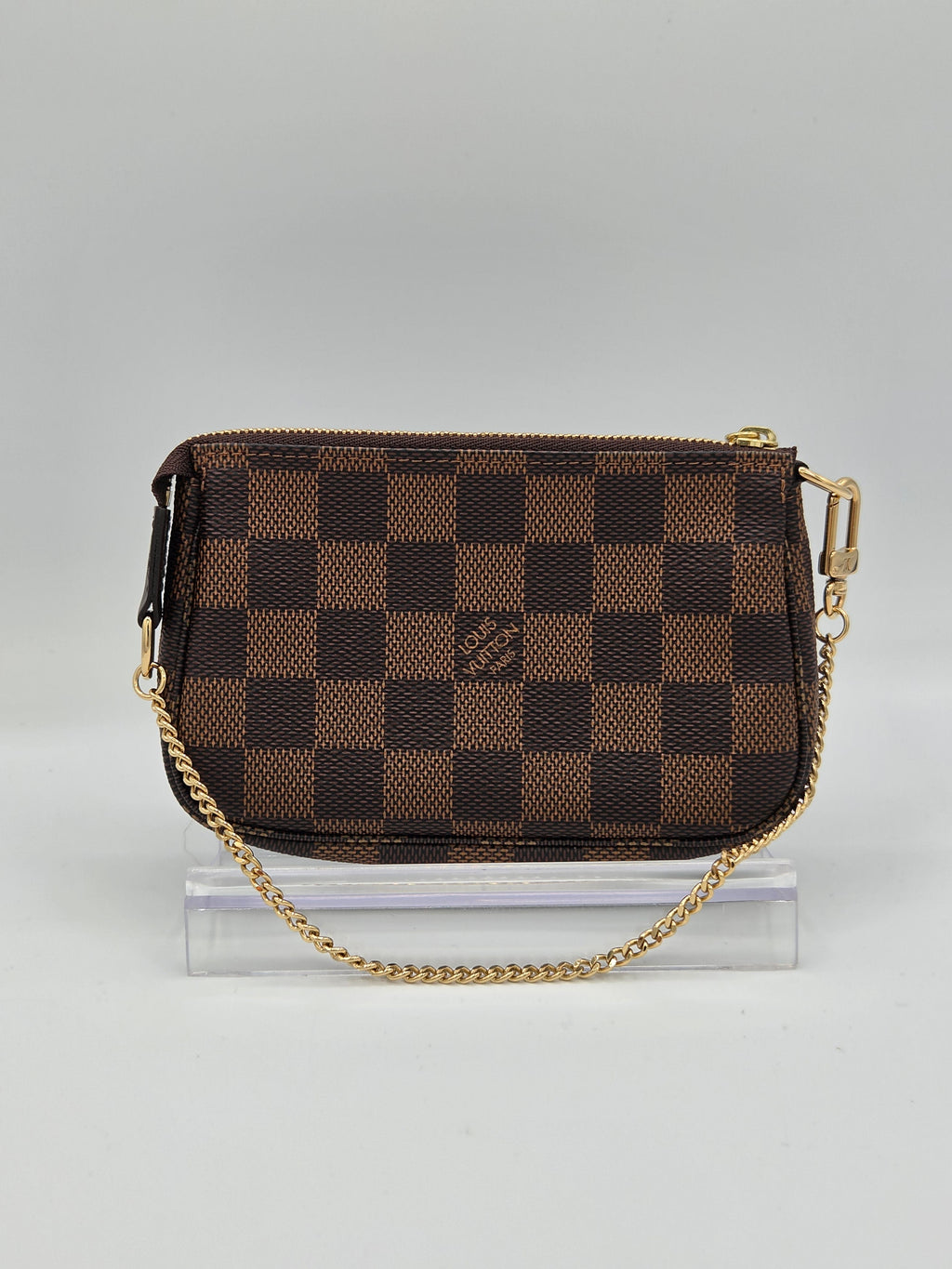 Brown checkered handbag with gold chain on a light gray background