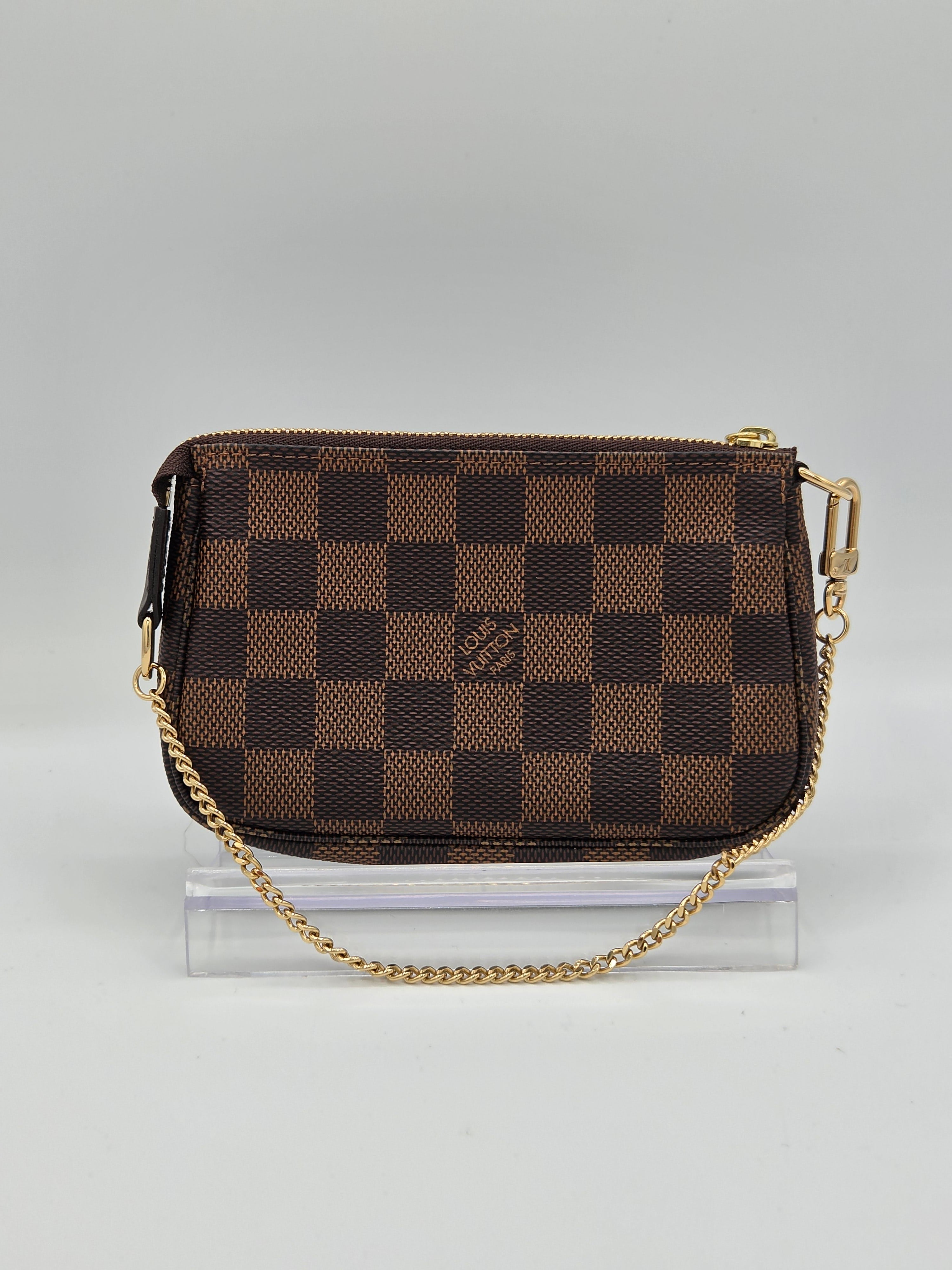 Brown checkered handbag with gold chain on a light gray background