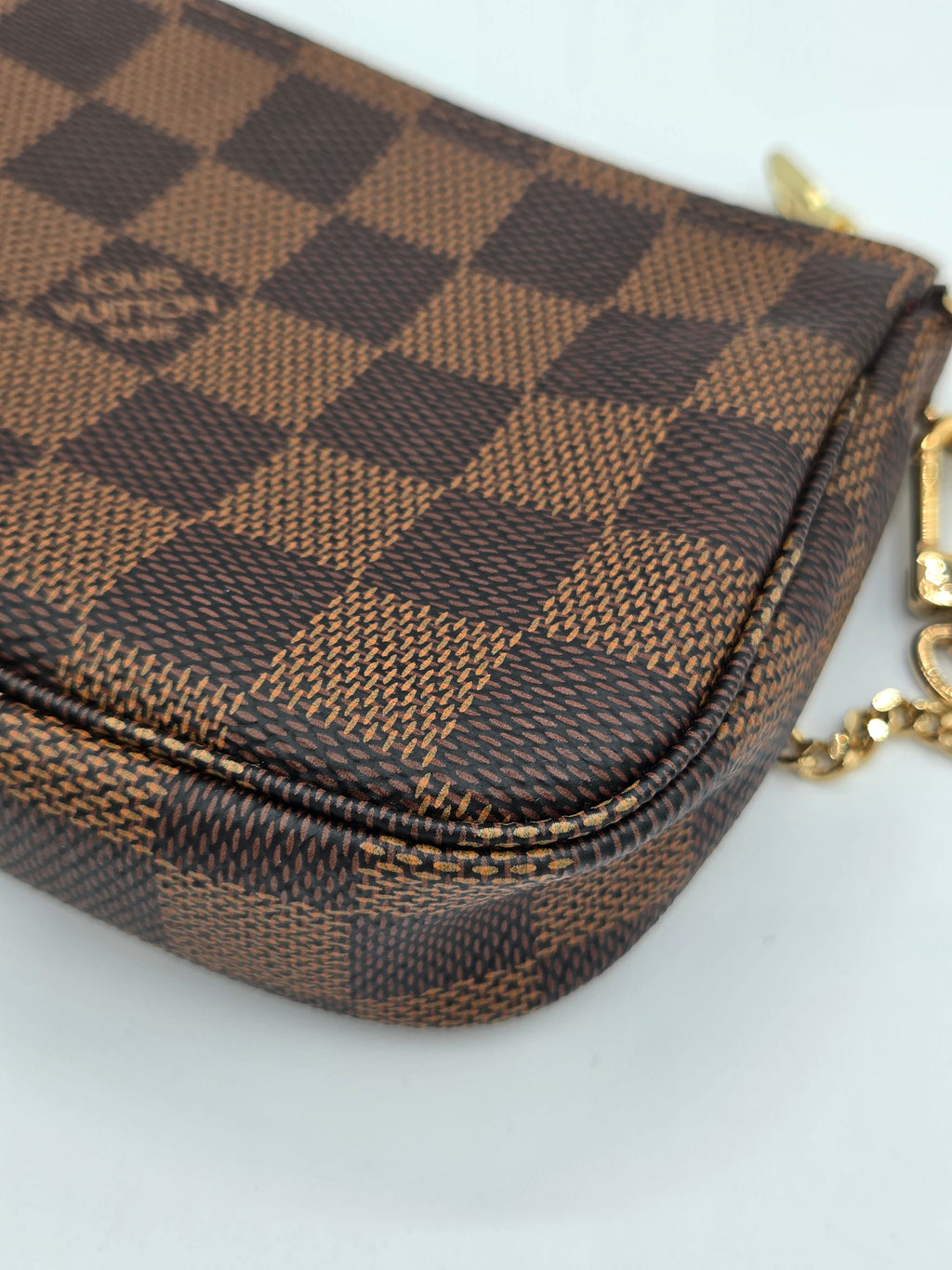 Brown checkered pouch with gold chain on a white background