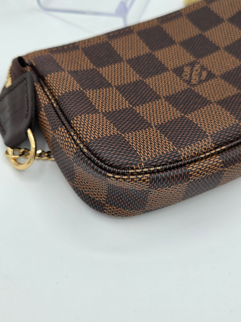 Brown checkered handbag with gold zipper on a light gray background