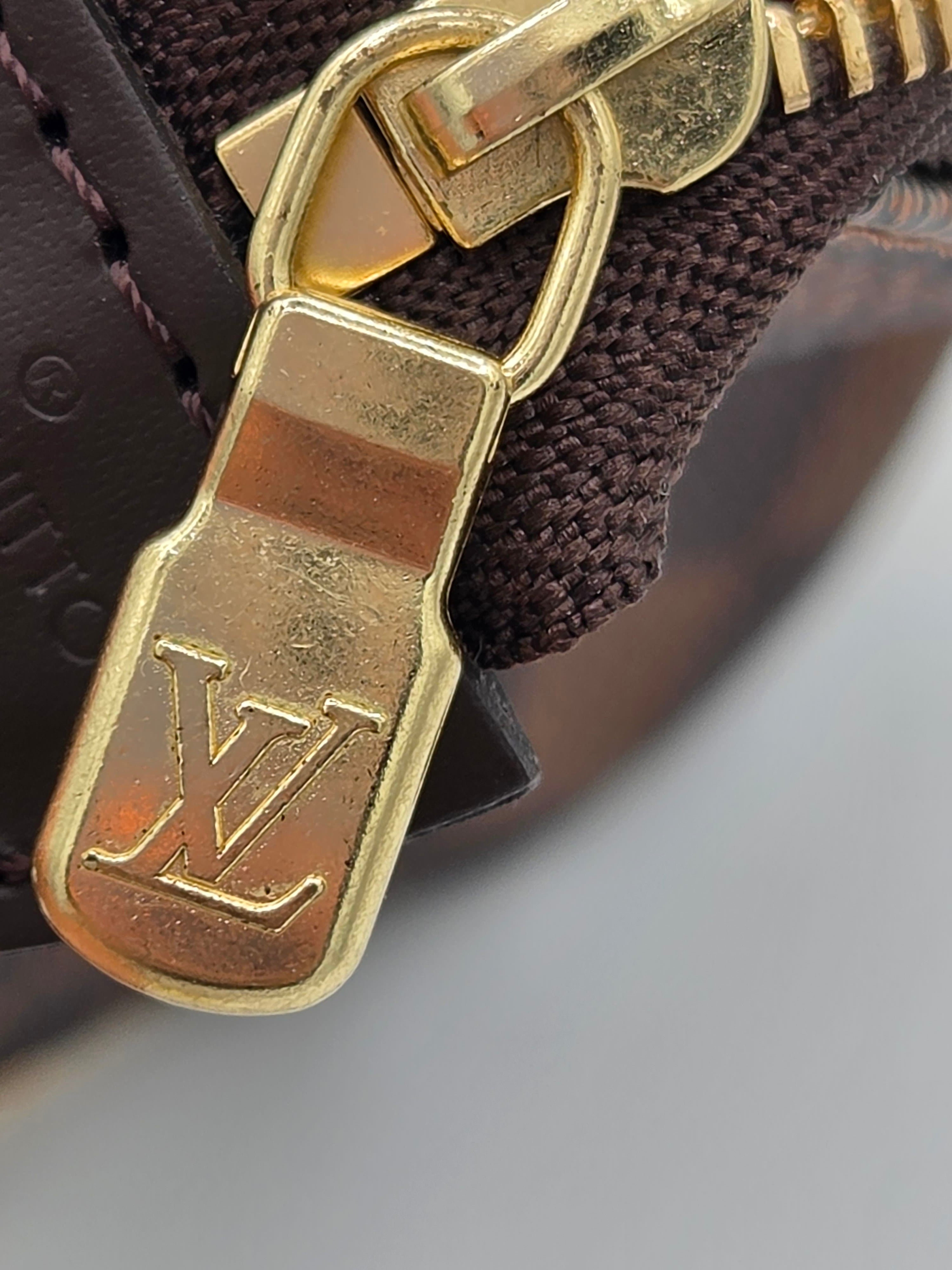 Close-up of a gold zipper pull on a brown fabric background