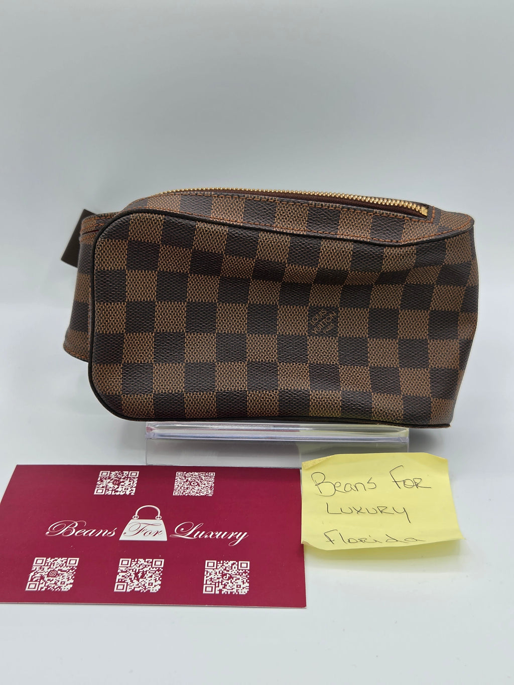 Brown checkered pouch with a card and note on a gray background