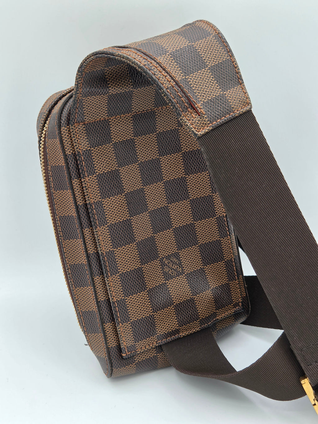 Brown checkered bag with a strap on a light gray background