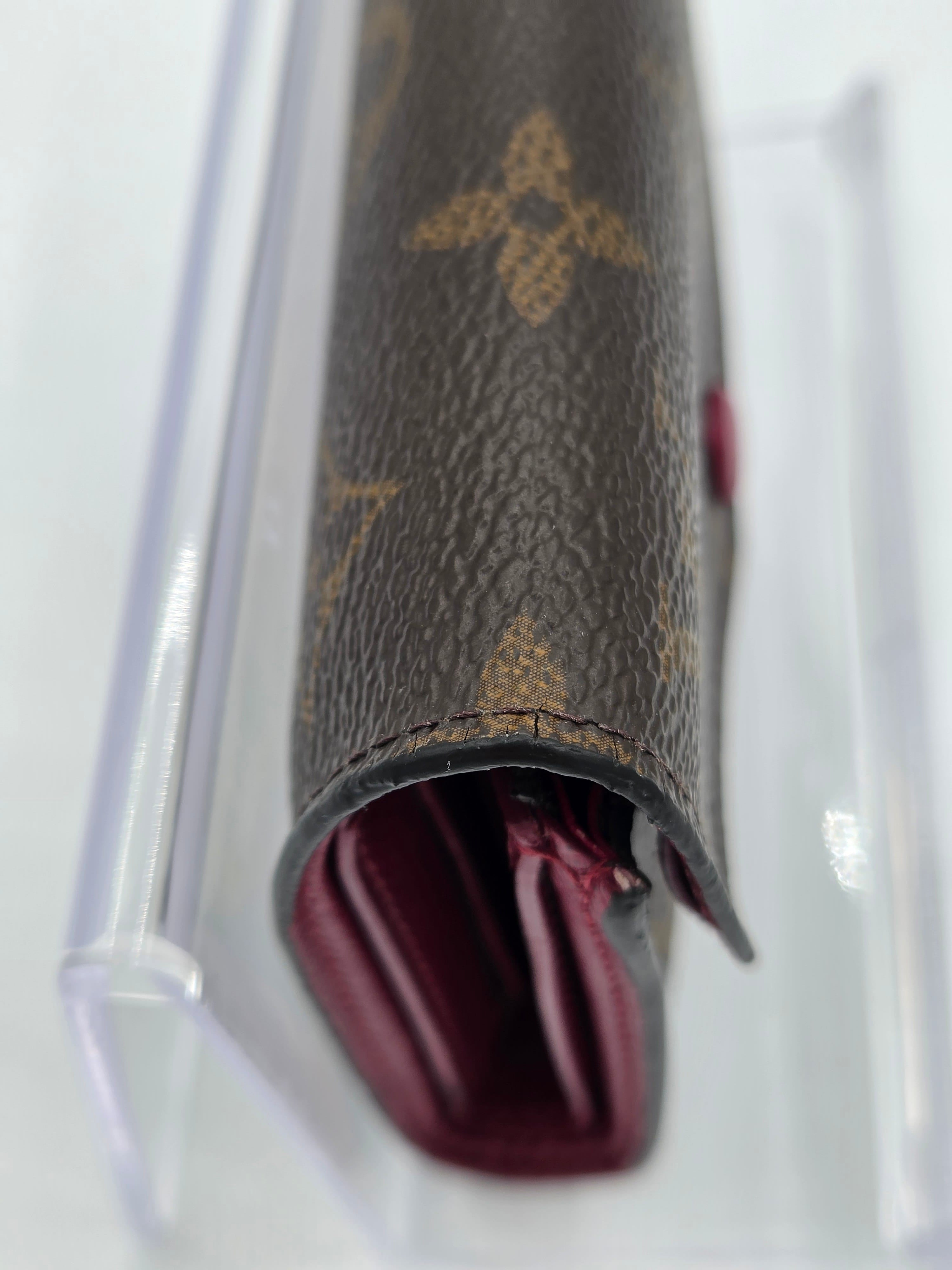 Close-up of a brown leather wallet with a visible brand logo on a white background