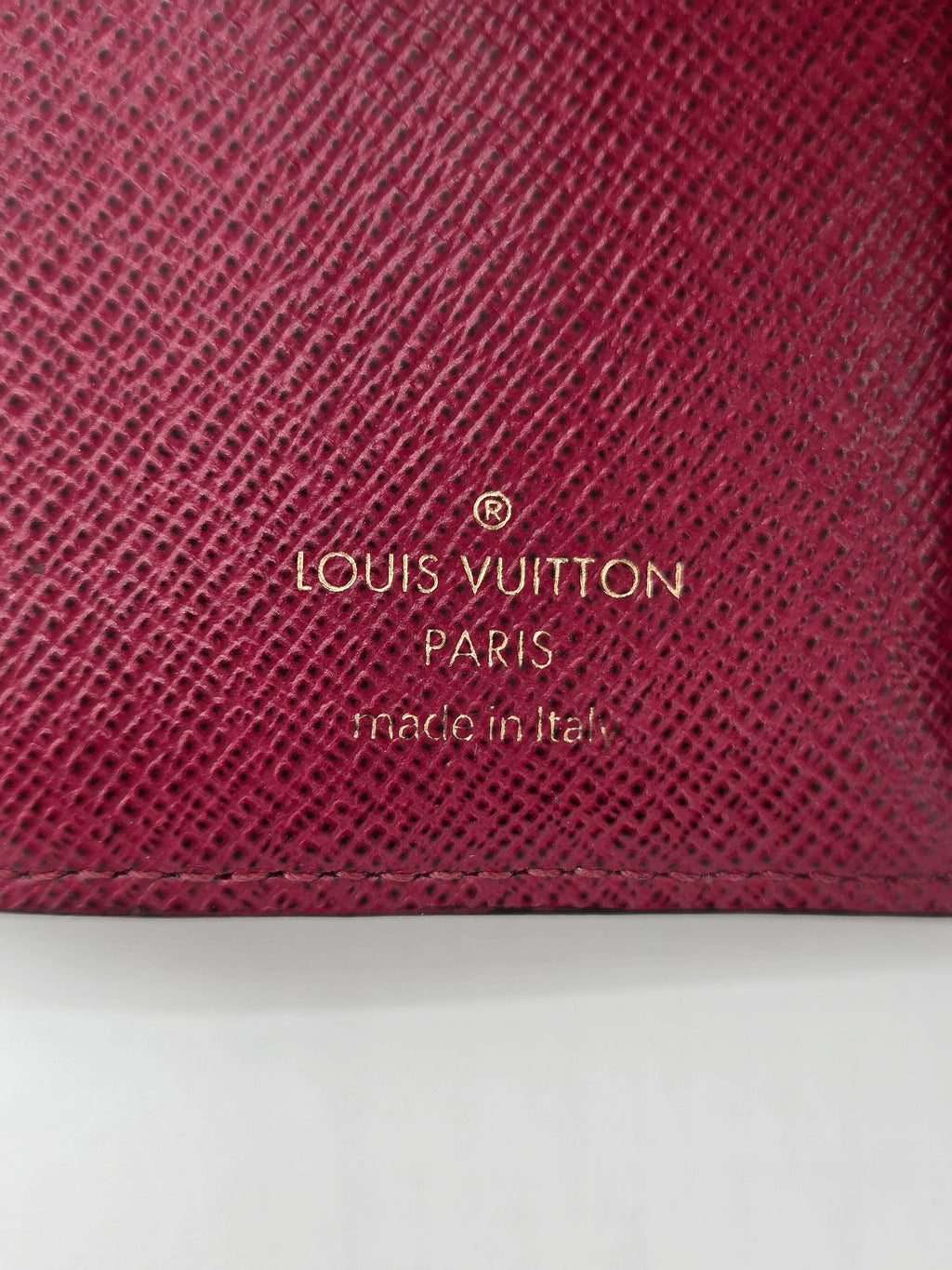 Close-up of a maroon Louis Vuitton wallet with gold lettering.