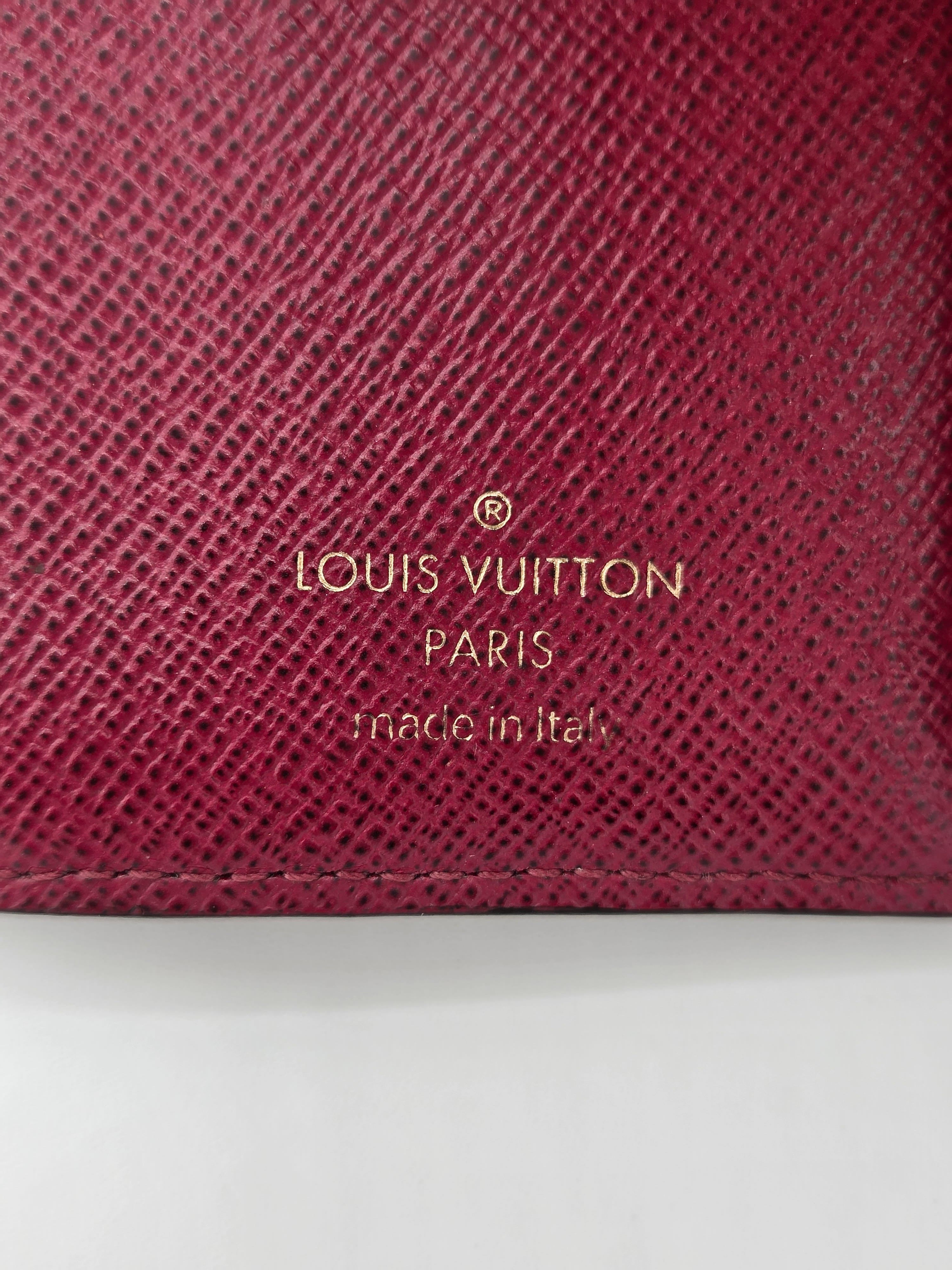 Close-up of a maroon Louis Vuitton wallet with gold lettering.
