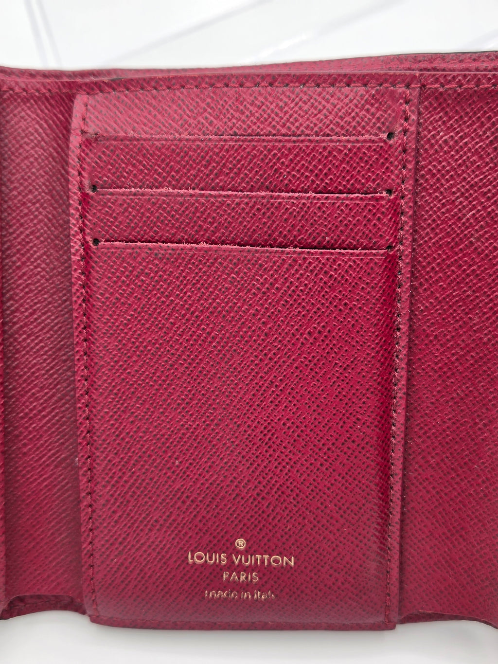 Close-up of a maroonLouis Vuitton wallet with visible branding.