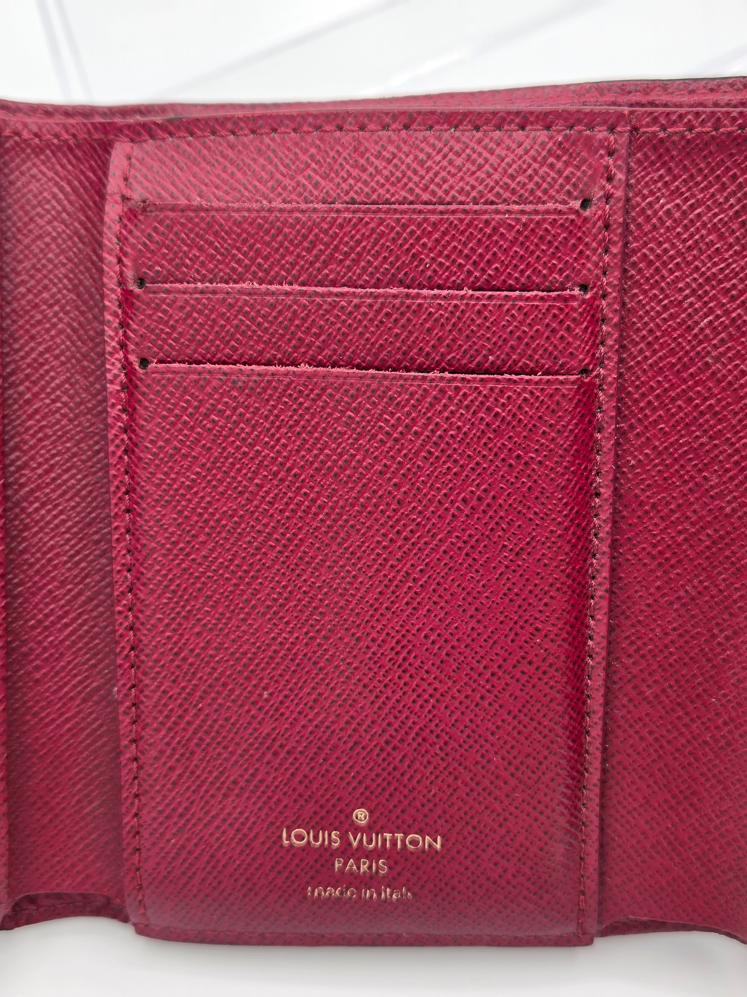 Close-up of a maroonLouis Vuitton wallet with visible branding.
