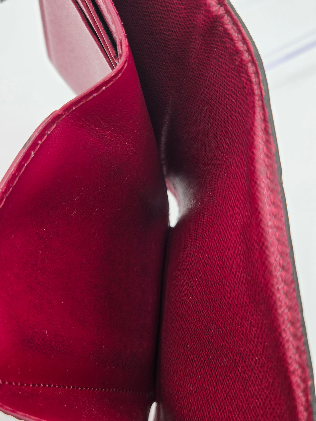 Close-up of a red leather bag with visible stitching on a white background
