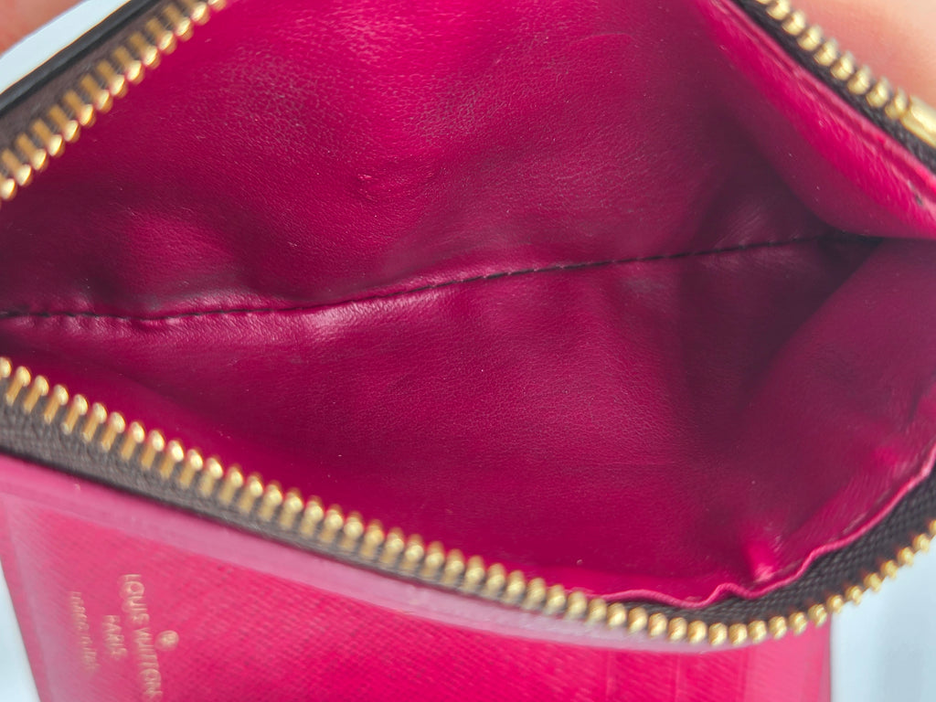 Close-up of a red handbag with gold zipper, brand name visible.