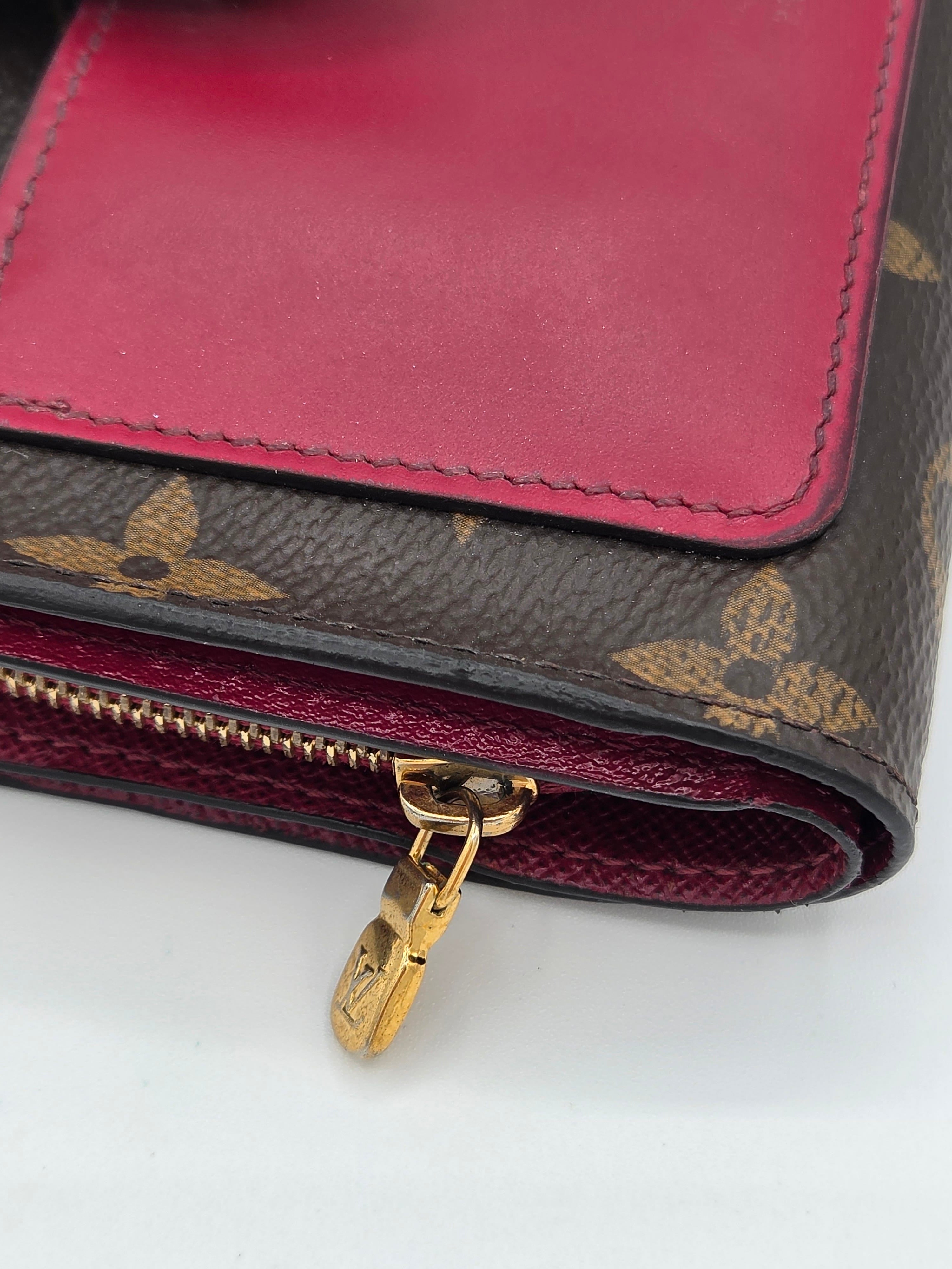 Close-up of a Louis Vuitton wallet with monogram pattern and red interior.