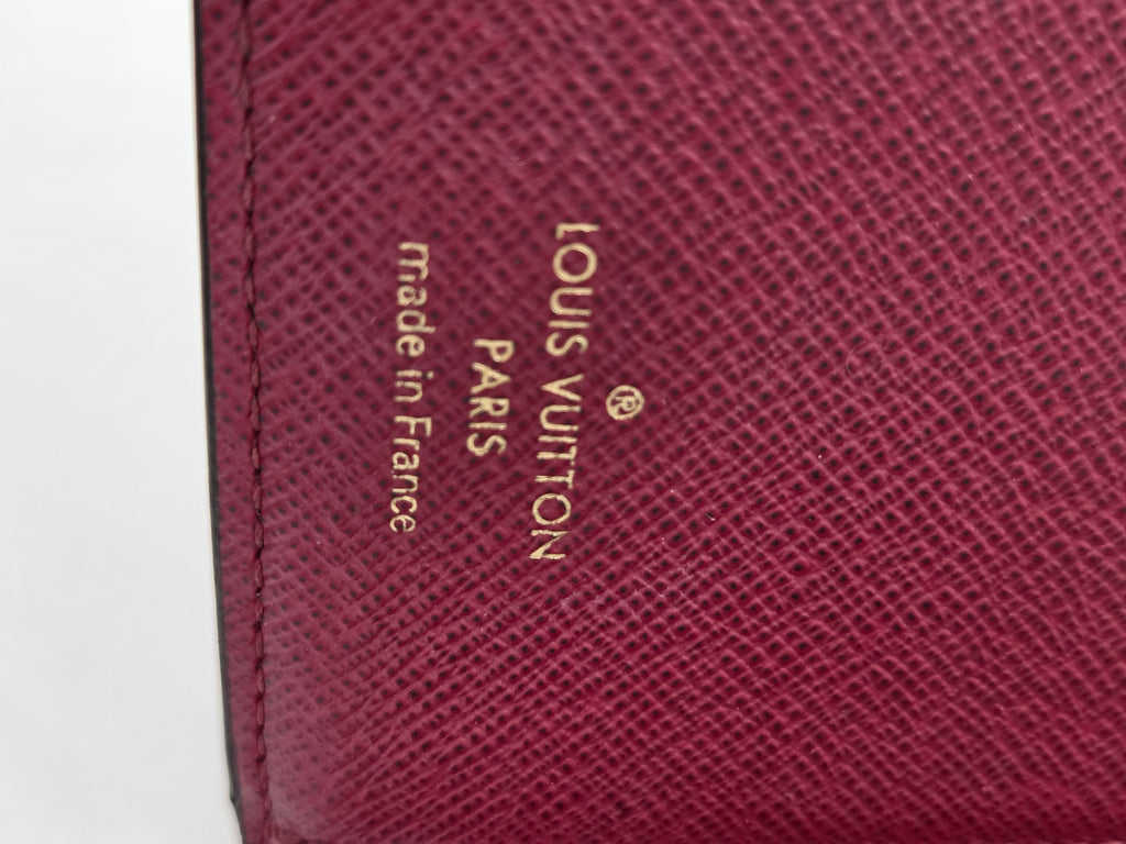 Close-up of a Louis Vuitton wallet with gold lettering on a white background