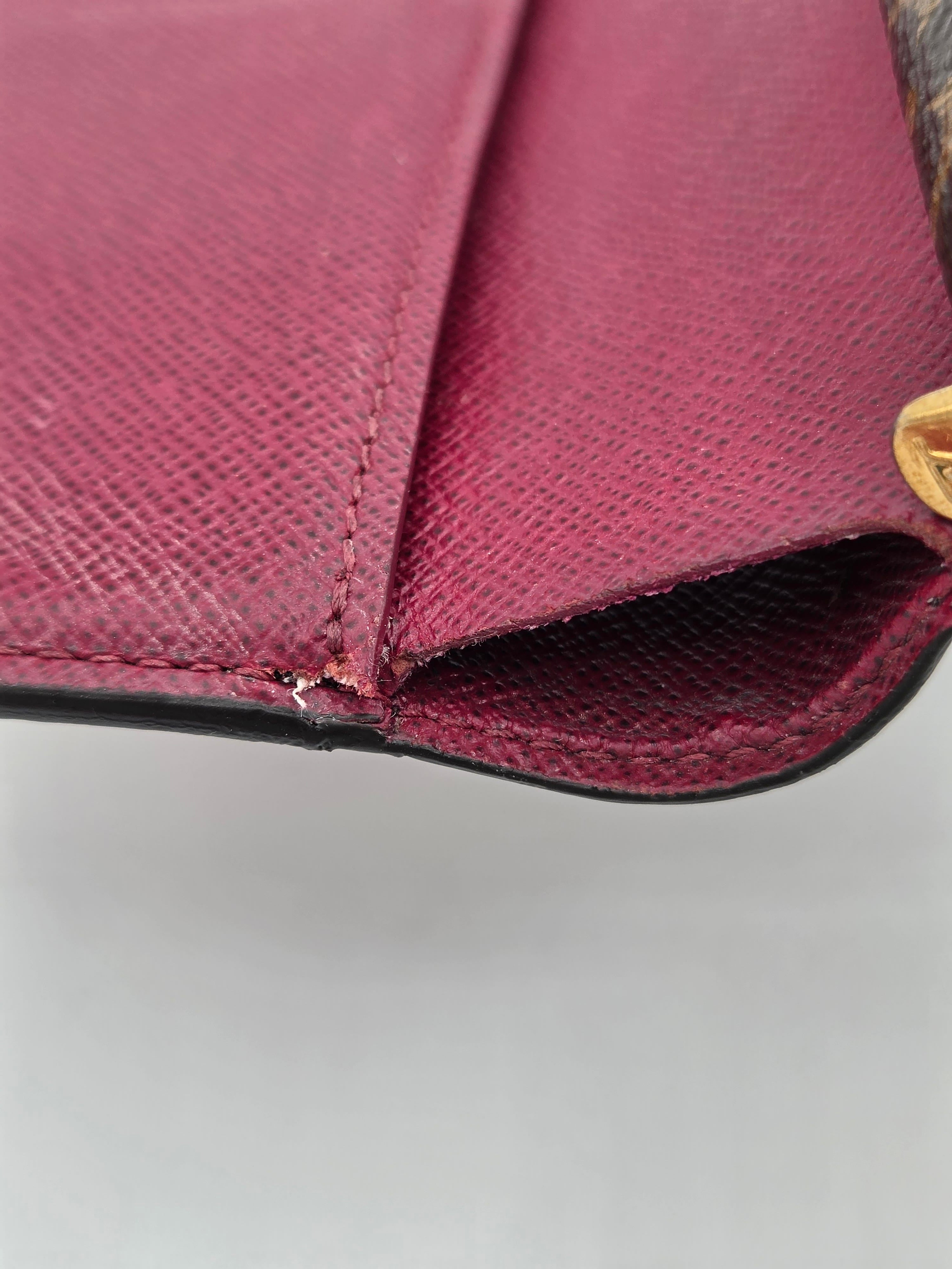 Close-up of a maroon handbag with a gold clasp on a gray background