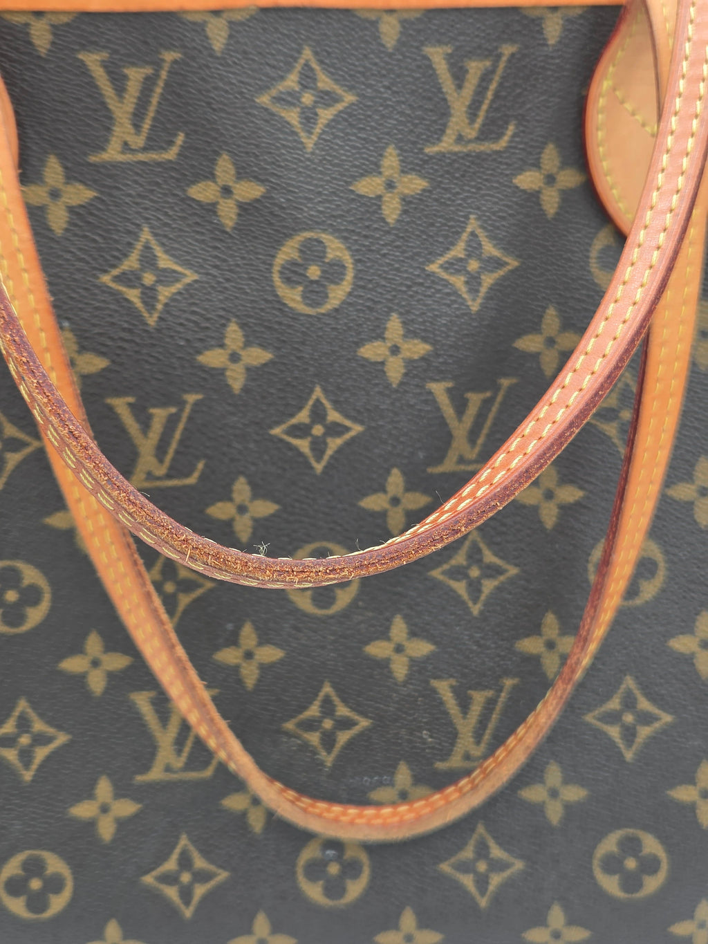 Close-up of a Louis Vuitton handbag with monogram pattern and brown leather handle.