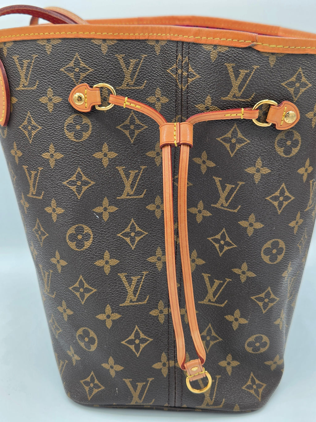 Designer handbag with monogram pattern on a light blue background