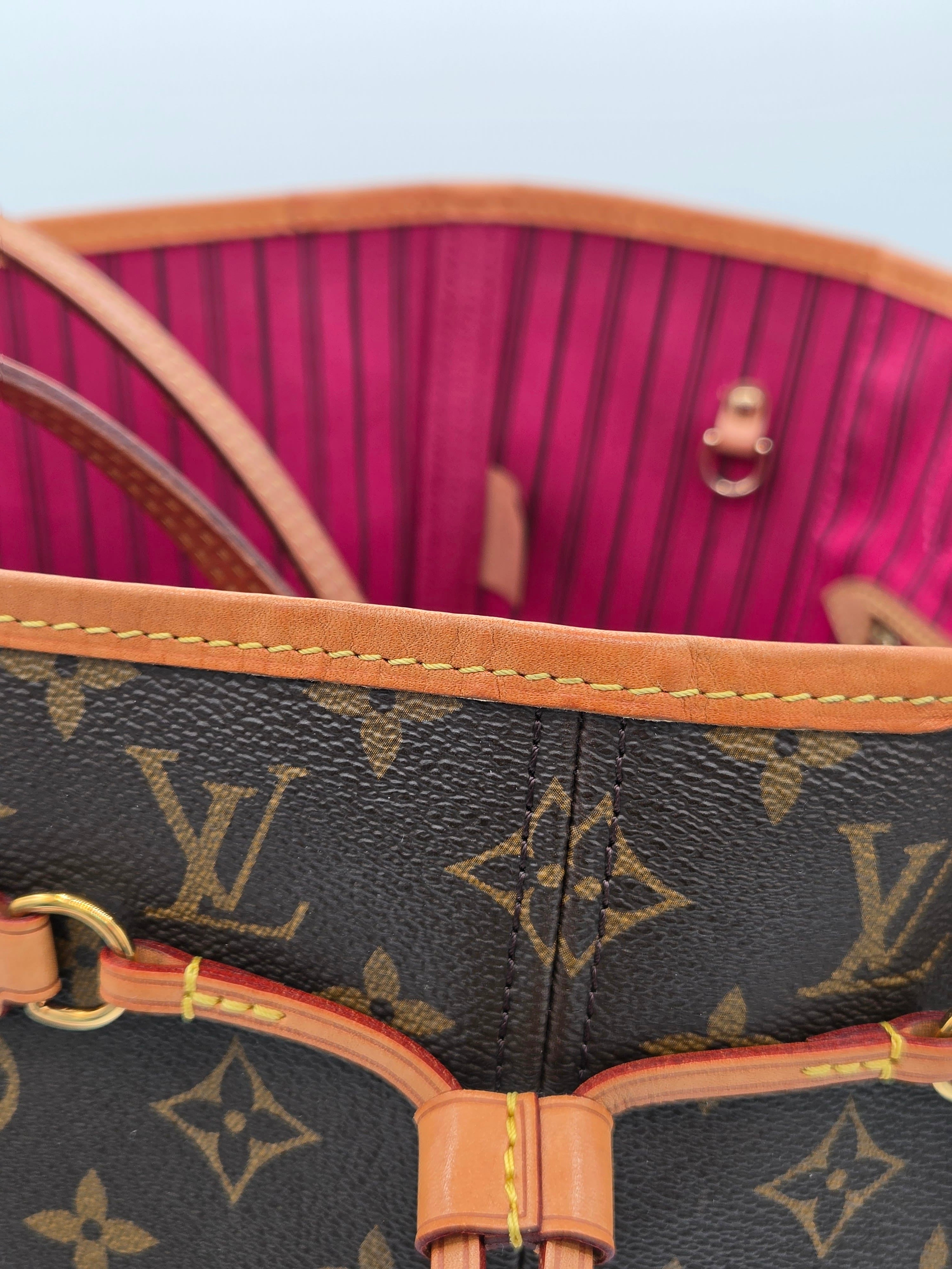 Louis Vuitton handbag with monogram pattern and brown handles on a pink and red striped background.