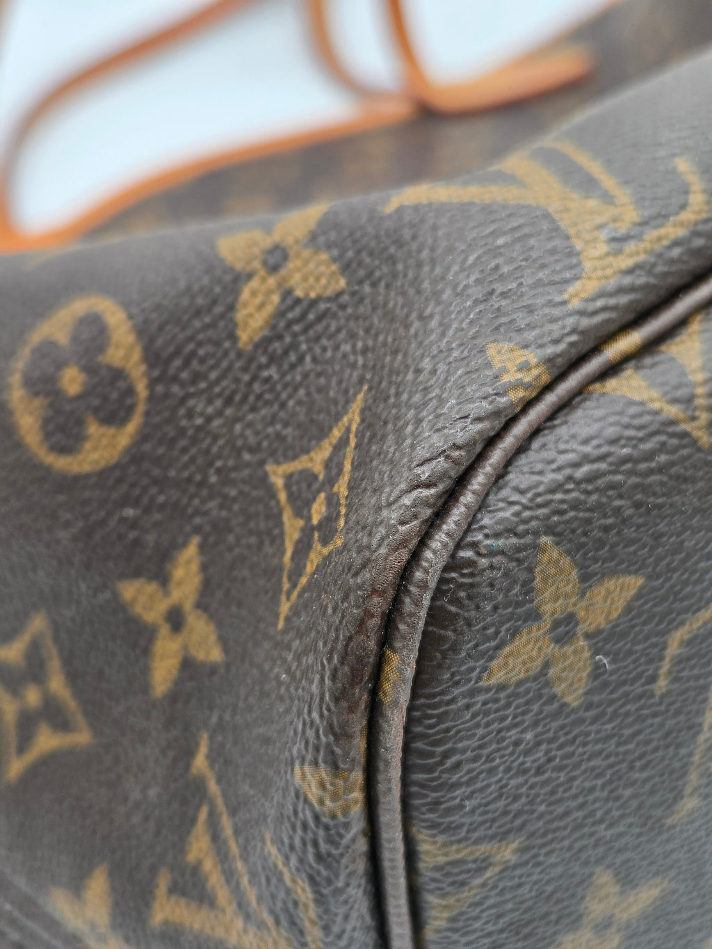 Close-up of a brown leather bag with gold monogram pattern