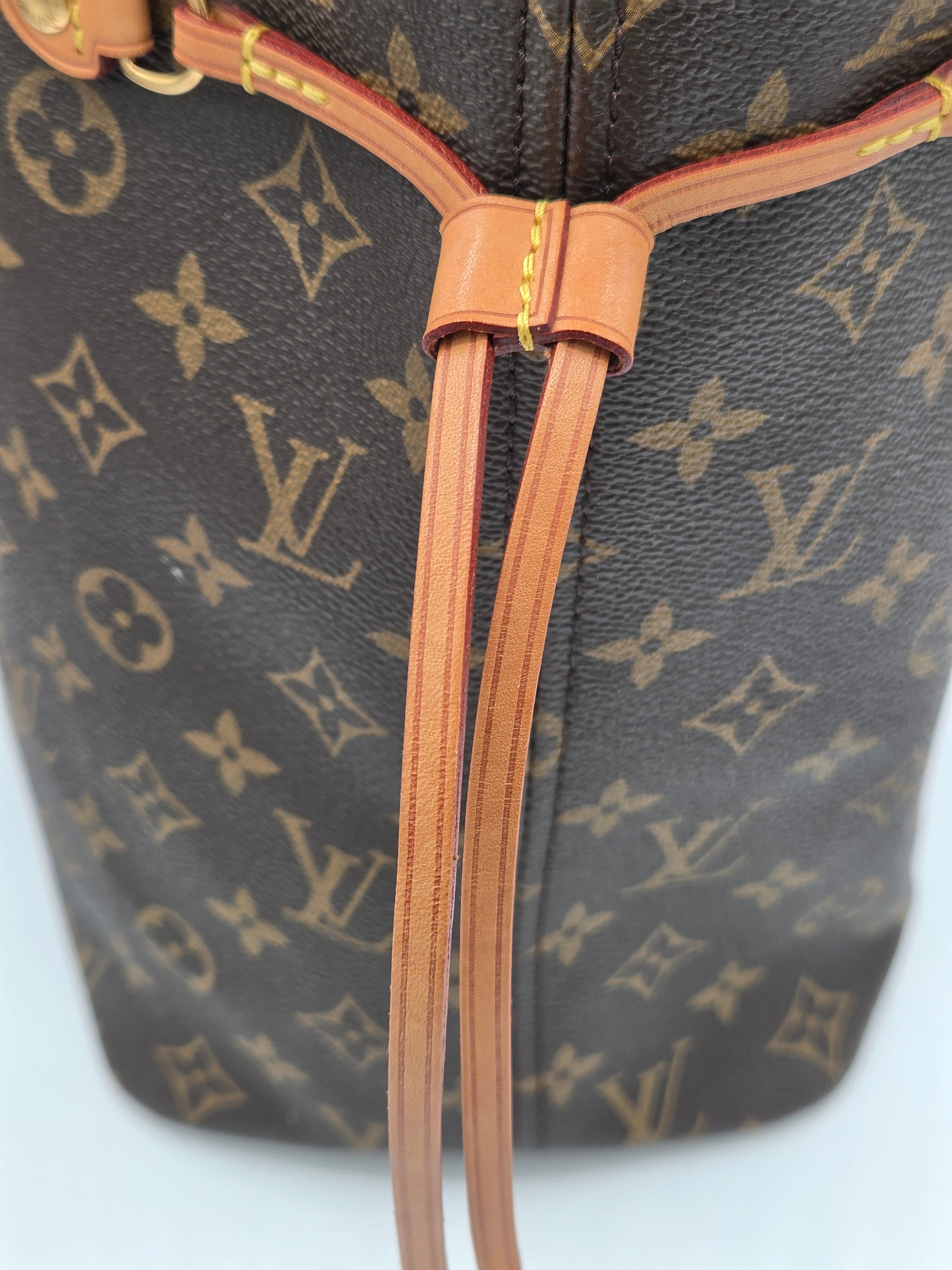 Close-up of a brown handbag with a visible brand logo on a light blue background