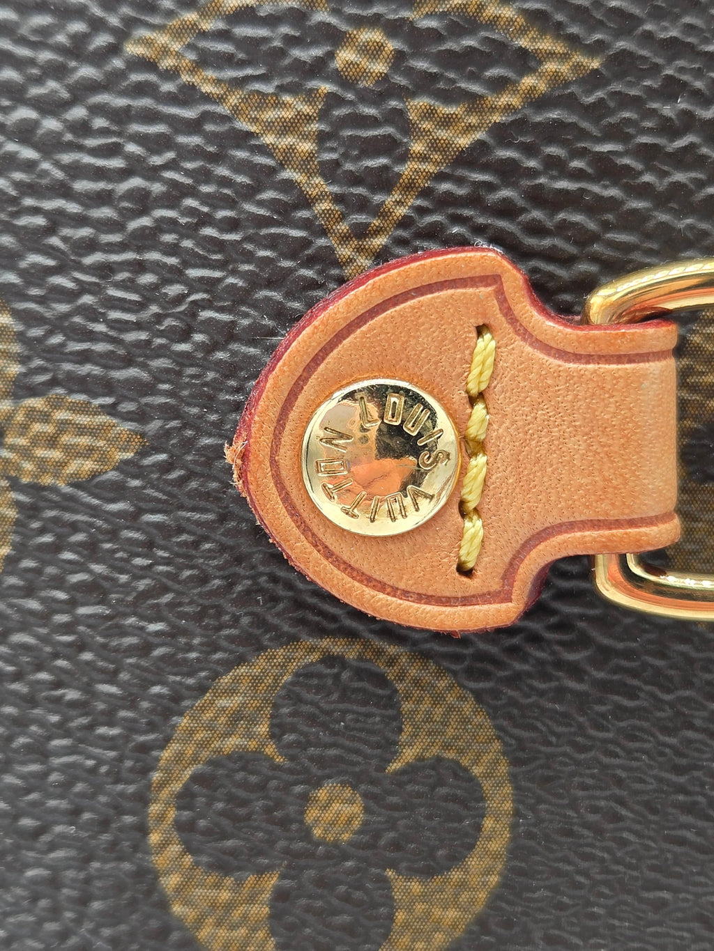 Close-up of a brown leather keychain with a gold tag on a textured surface.
