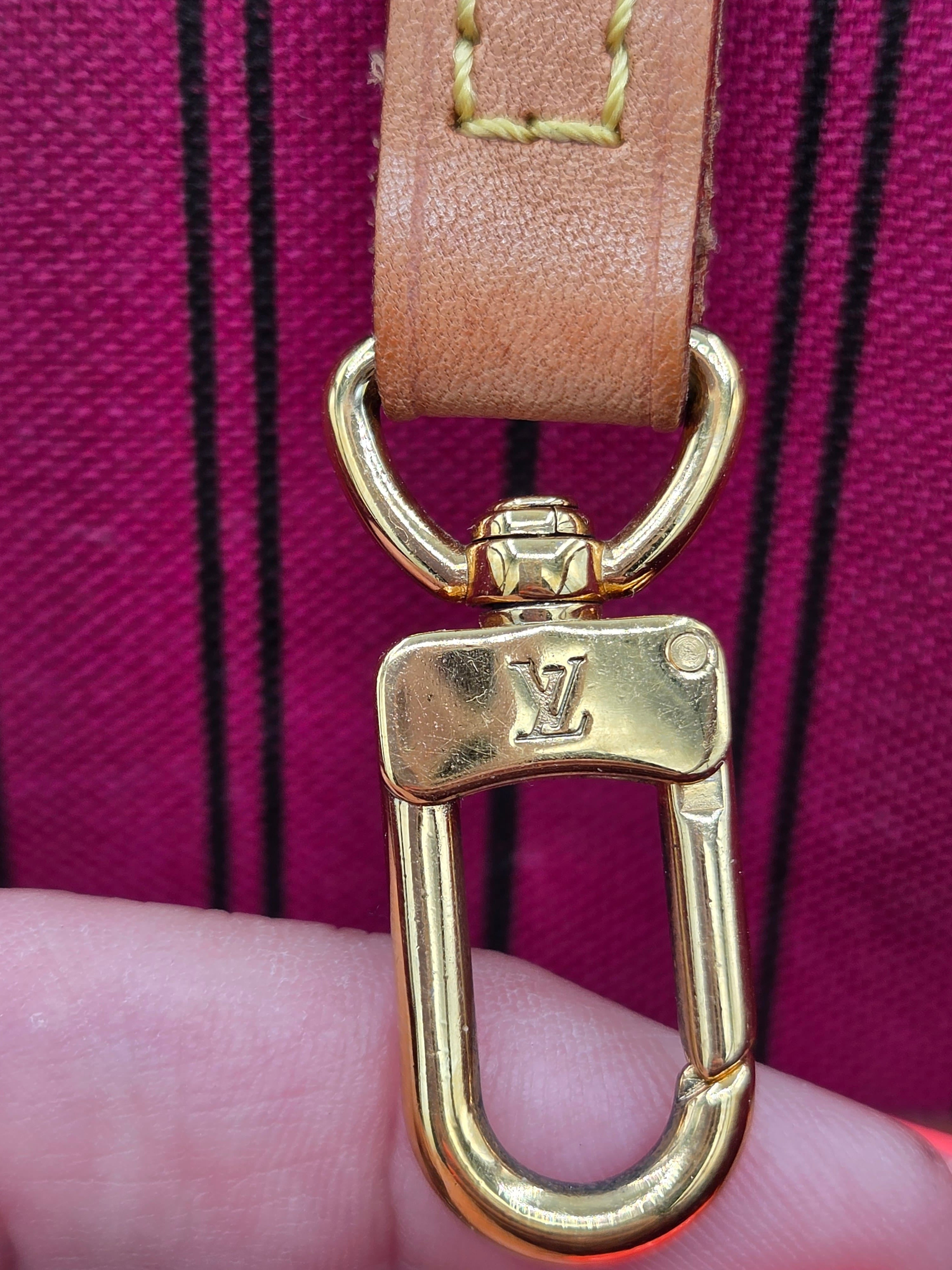 Gold hardware on a leather strap against a purple background