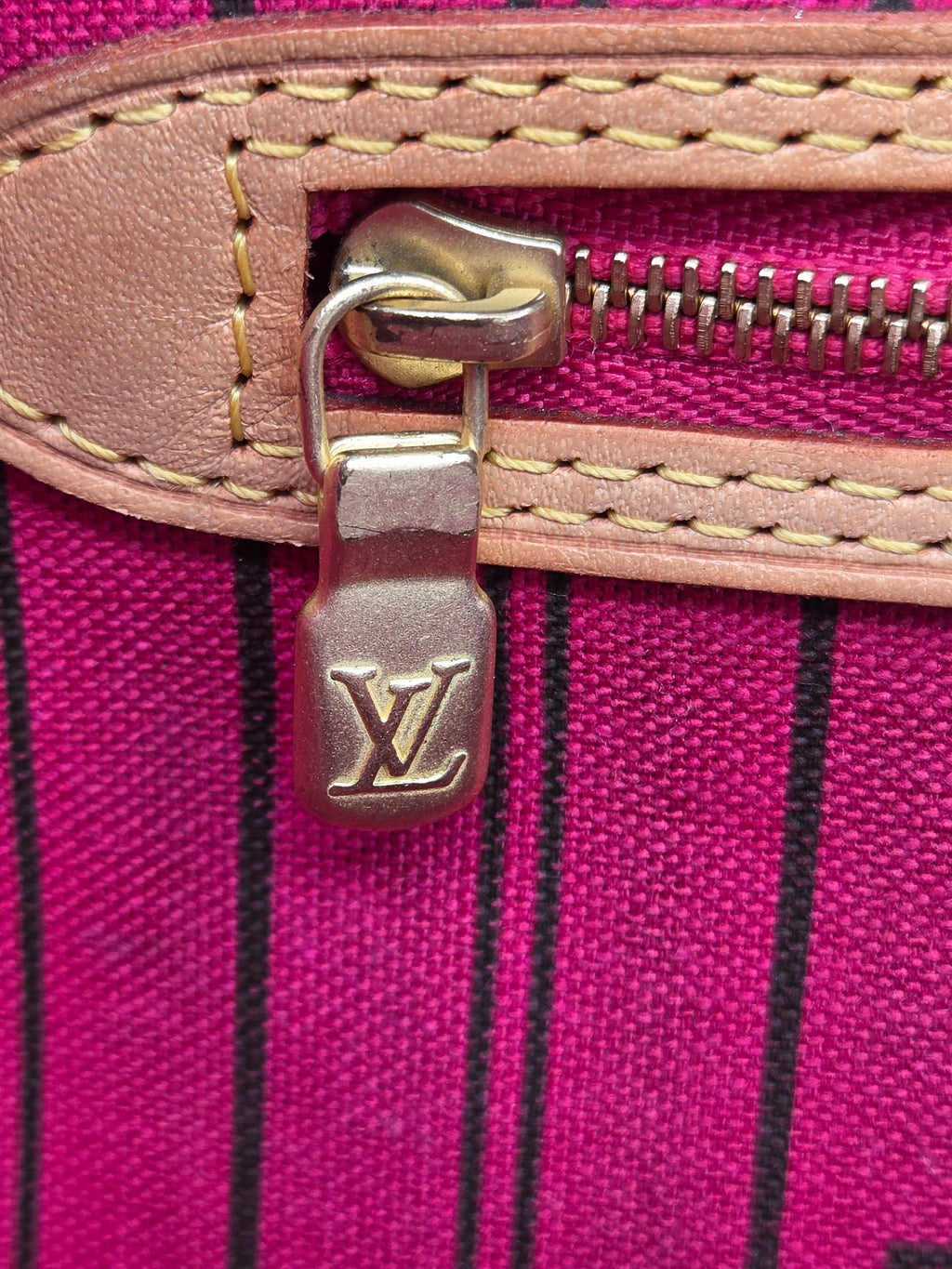 Close-up of a Louis Vuitton bag zipper with pink fabric background